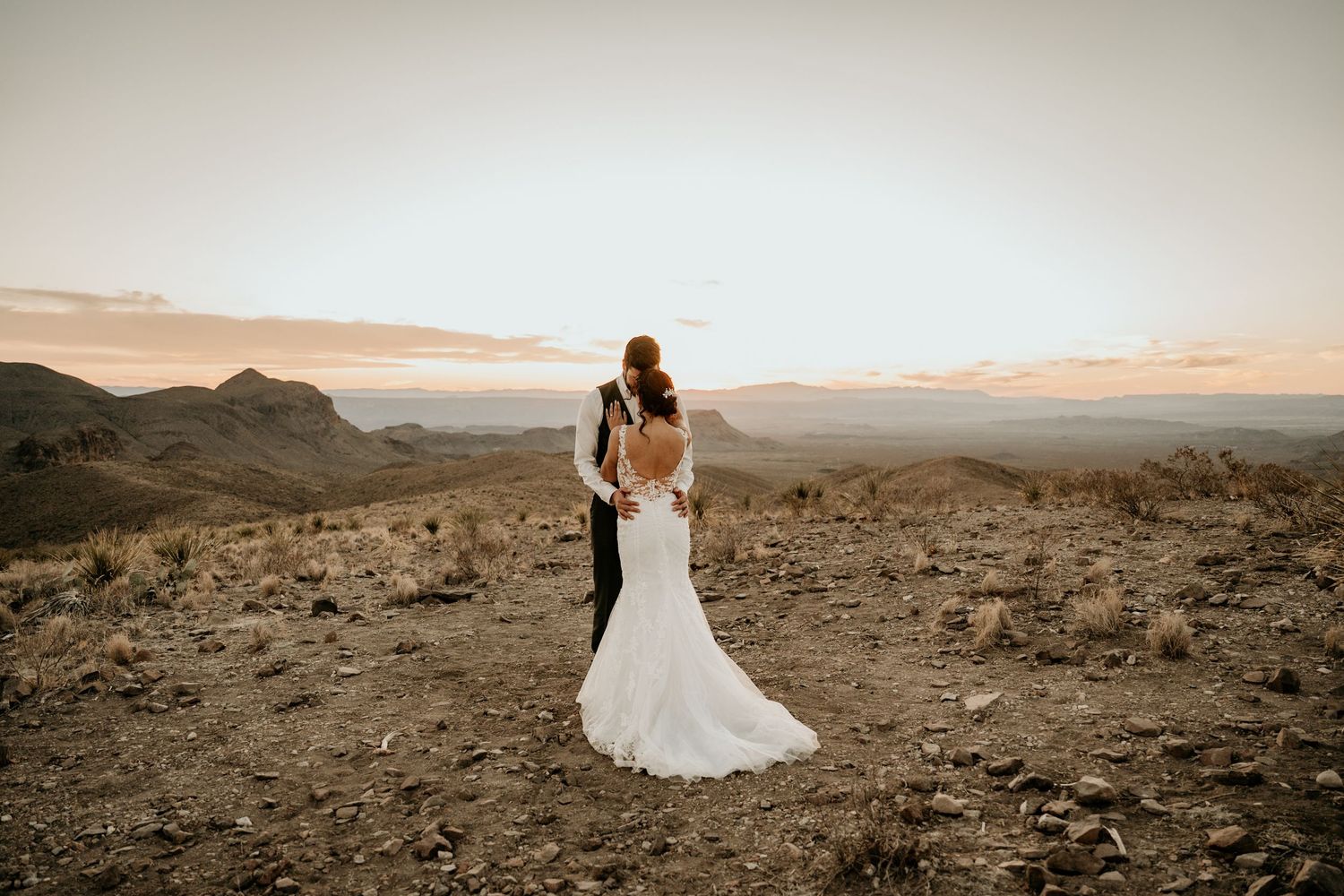 Elegant wedding photos taken in a dramatic desert landscape at sunset.
