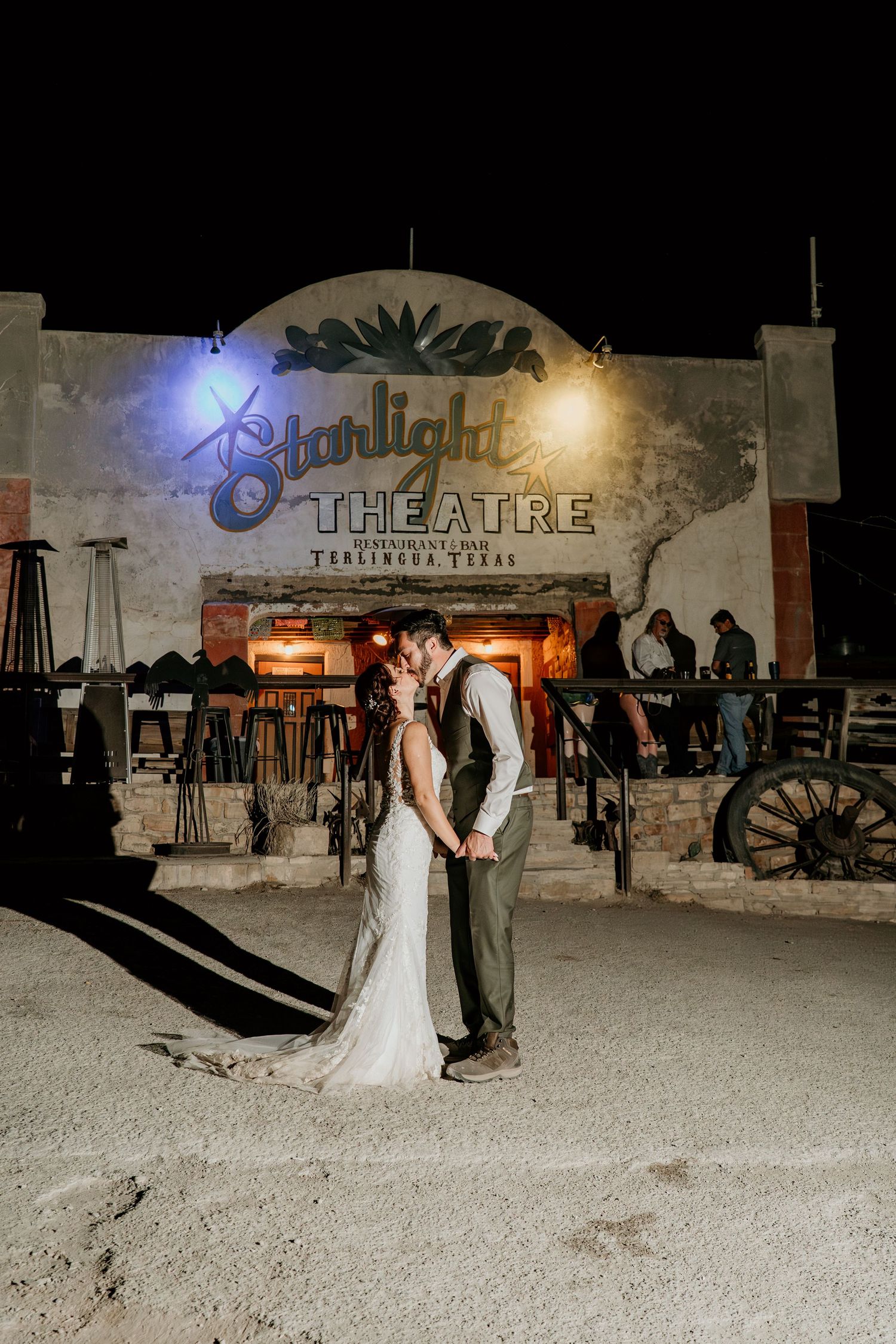 A couple shares a romantic moment at night in front of the illuminated Starlight Theatre sign.