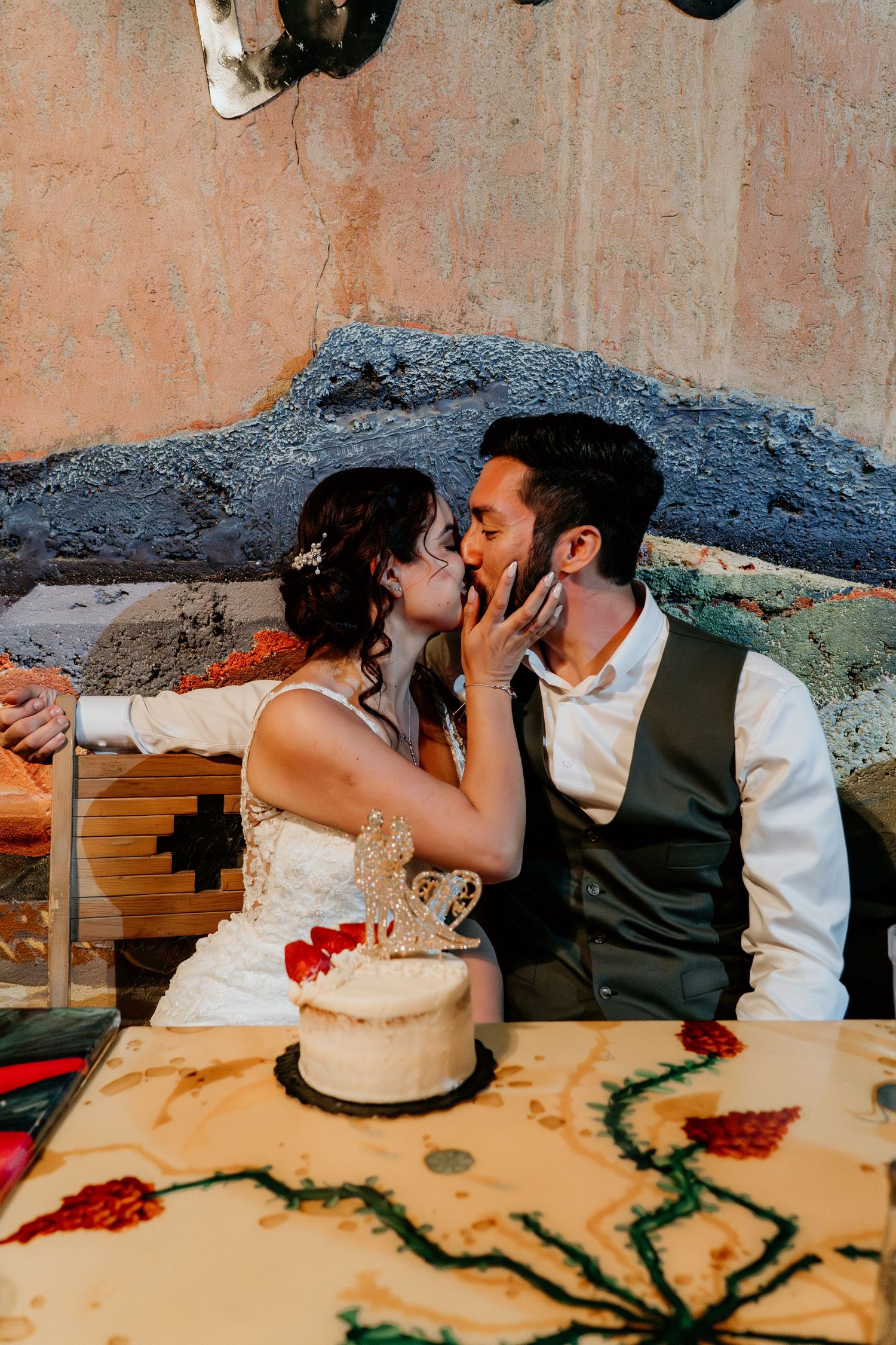 Couple sharing a romantic moment at their wedding reception table with cake and decorations.