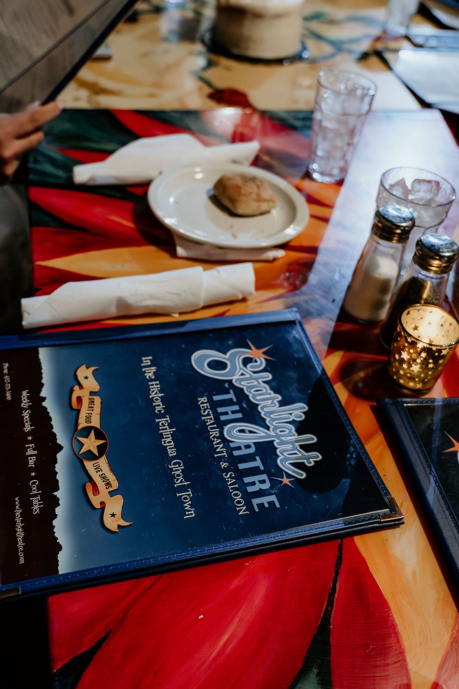 Blue wedding menus on red tablecloth with dining settings.