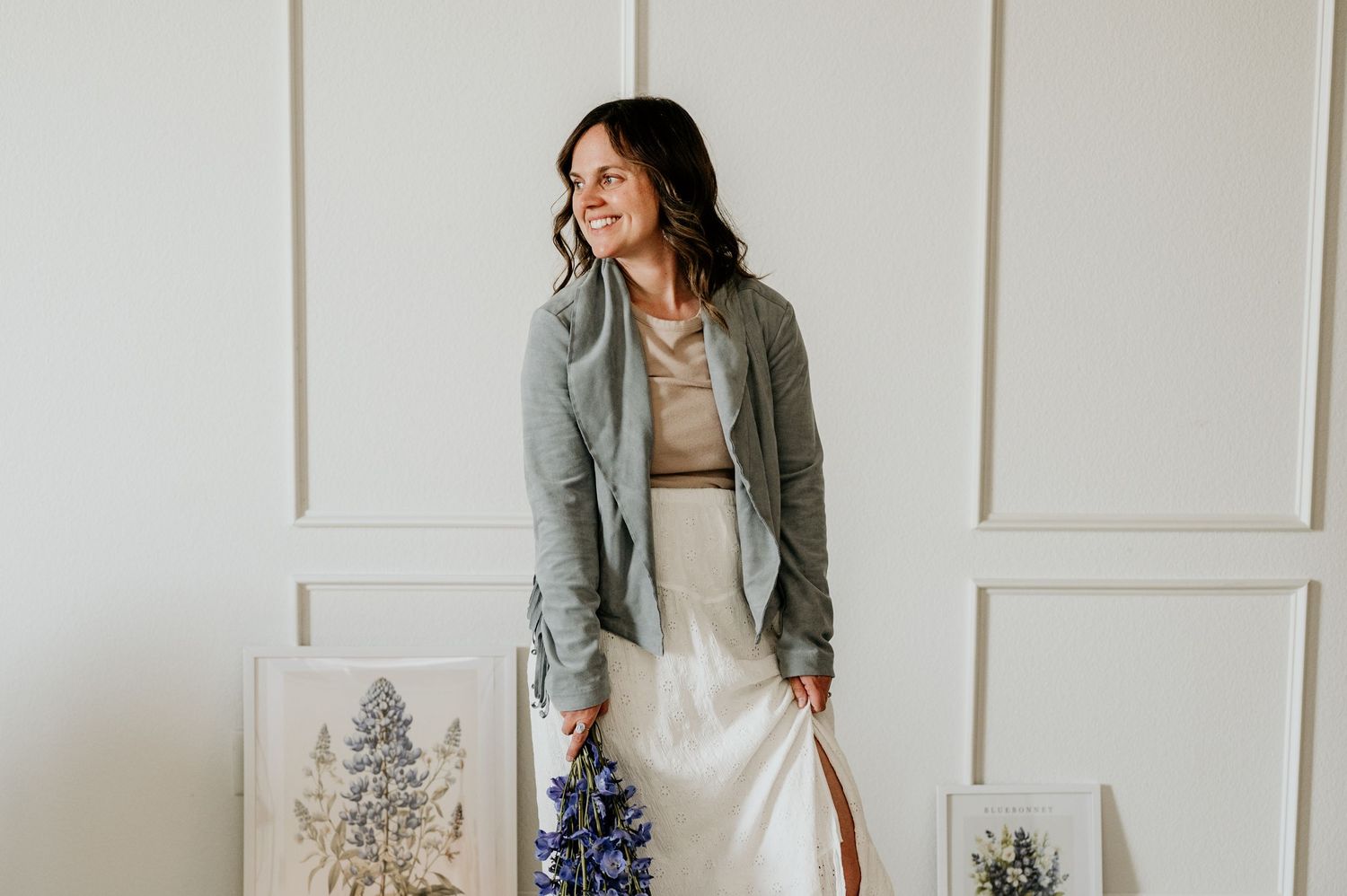 Stylish outfit featuring a gray blazer, white dress and brown boots against a white paneled wall.