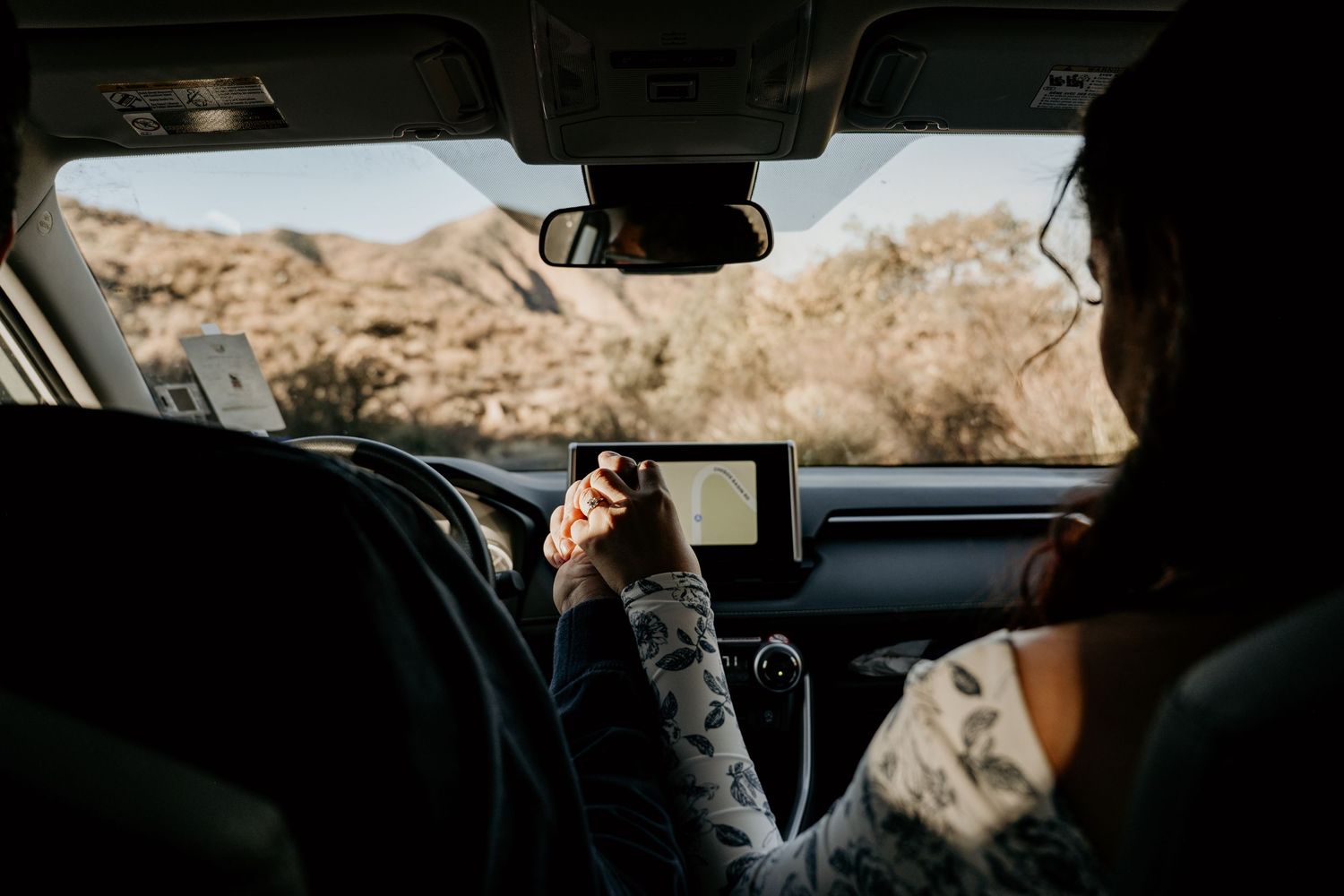 View from inside a car showing two people in front seats driving through Big Bend National Park.