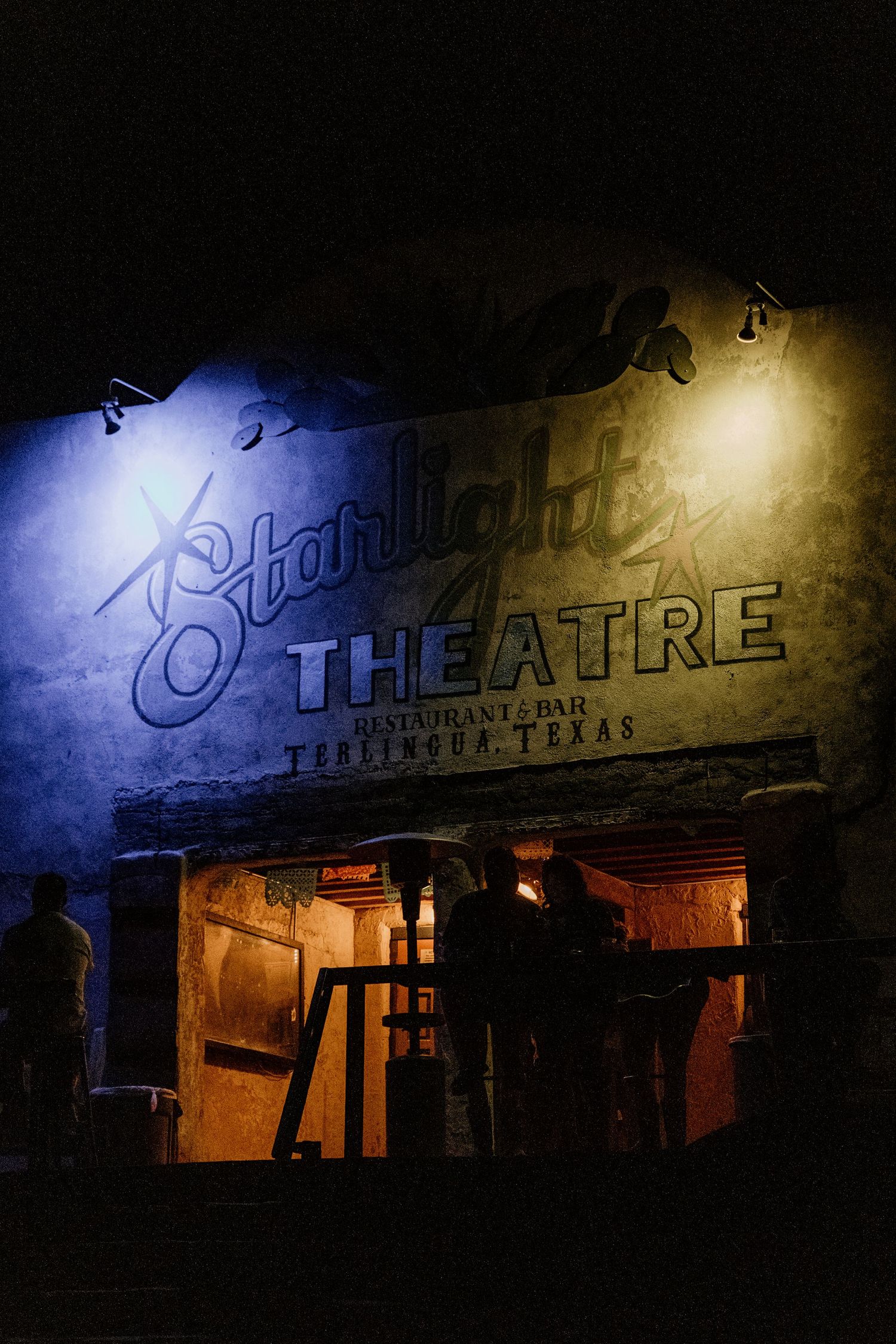 Illuminated vintage theatre sign at night with dramatic lighting and shadows.