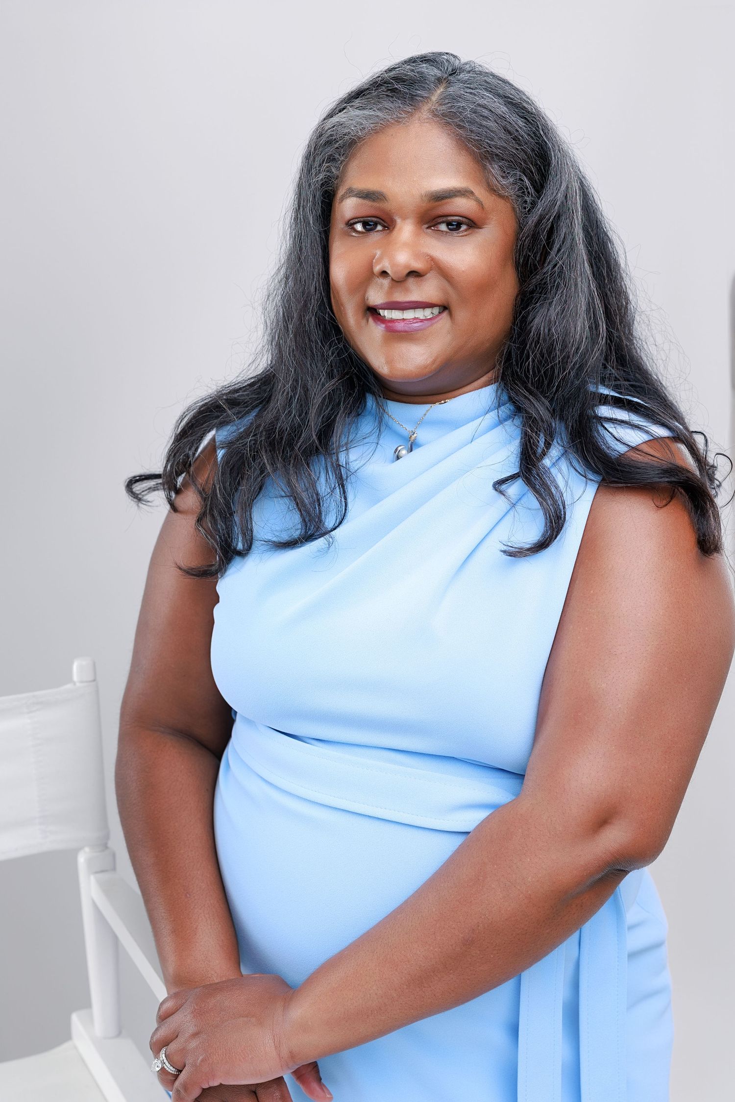 A person wearing a light blue sleeveless top poses confidently in a series of professional studio portraits.