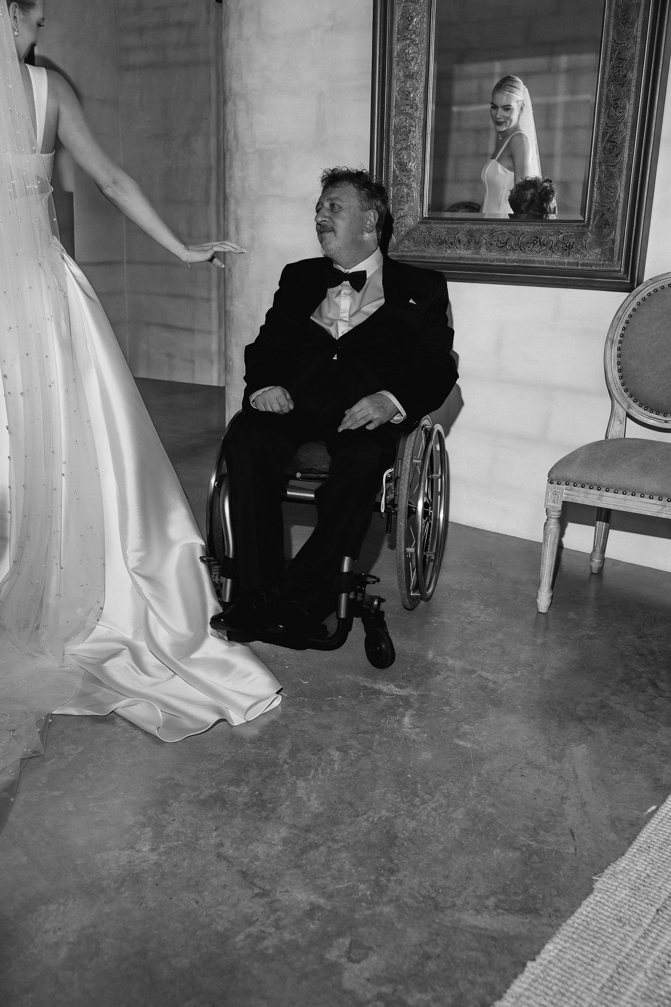 Emotional father in wheelchair sees his daughter in her wedding dress for the first time.