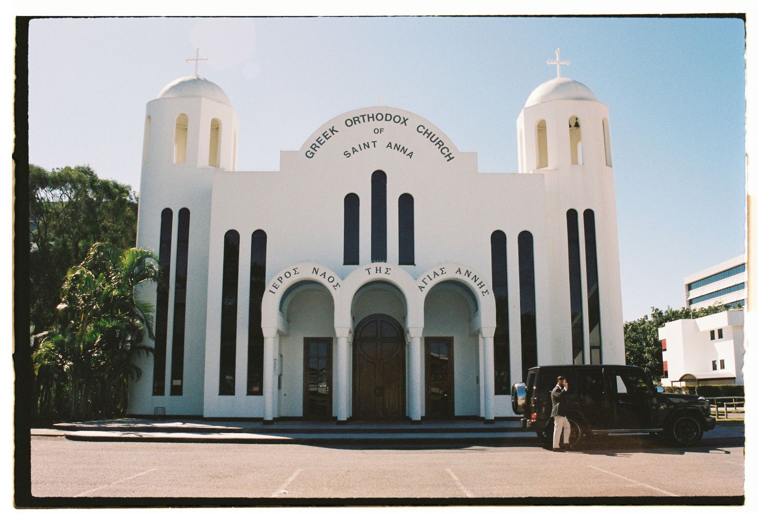 White Greek Orthodox Church of Saint Anna with twin domes and arched entrance.