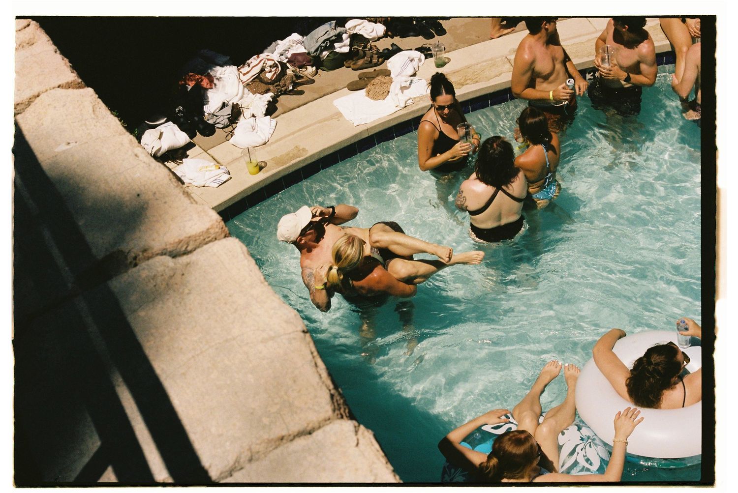 Aerial view of people enjoying a crowded outdoor swimming pool on a sunny day.
