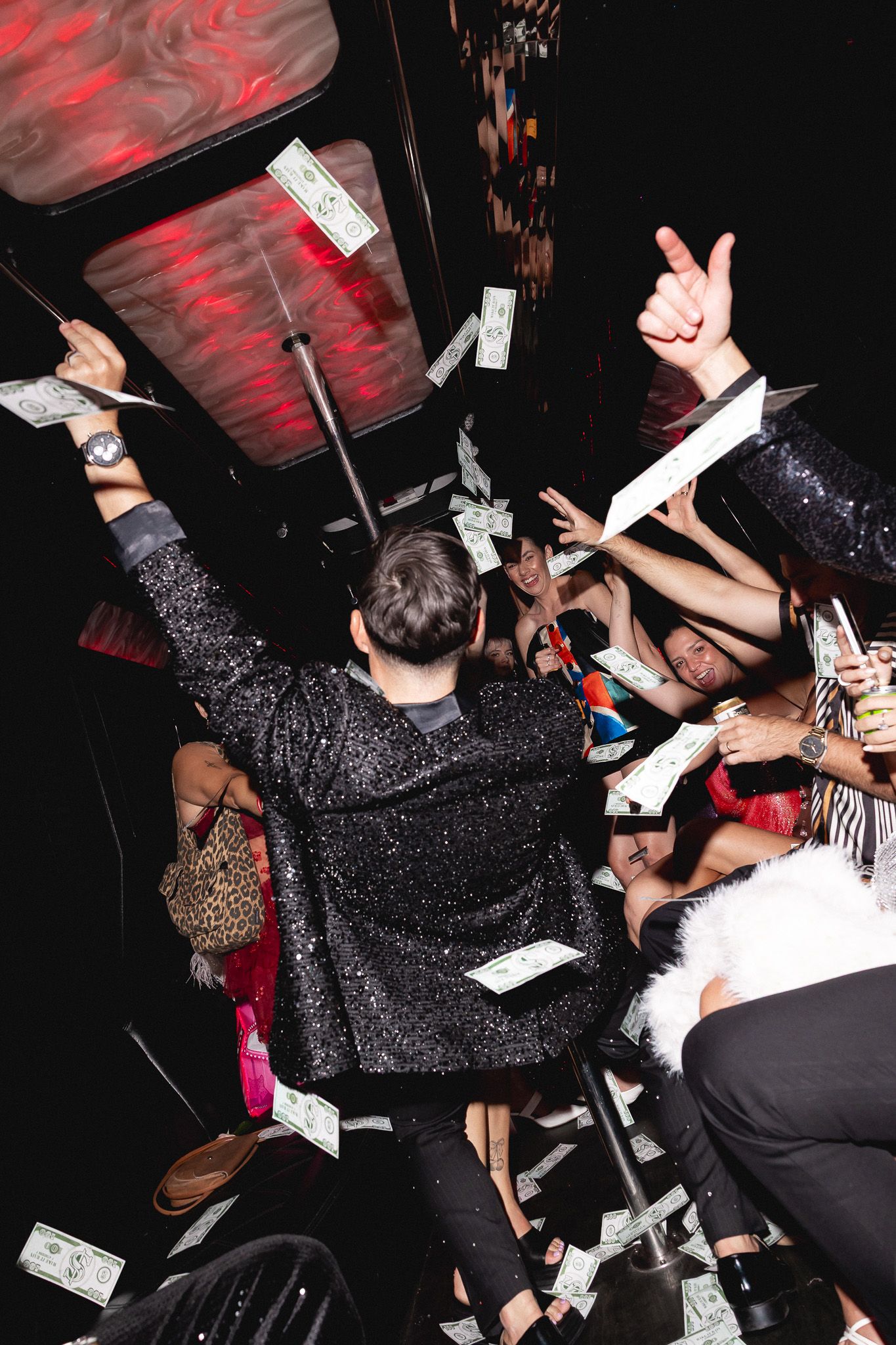 Party guests celebrate with flying money on a Las Vegas party bus at night.