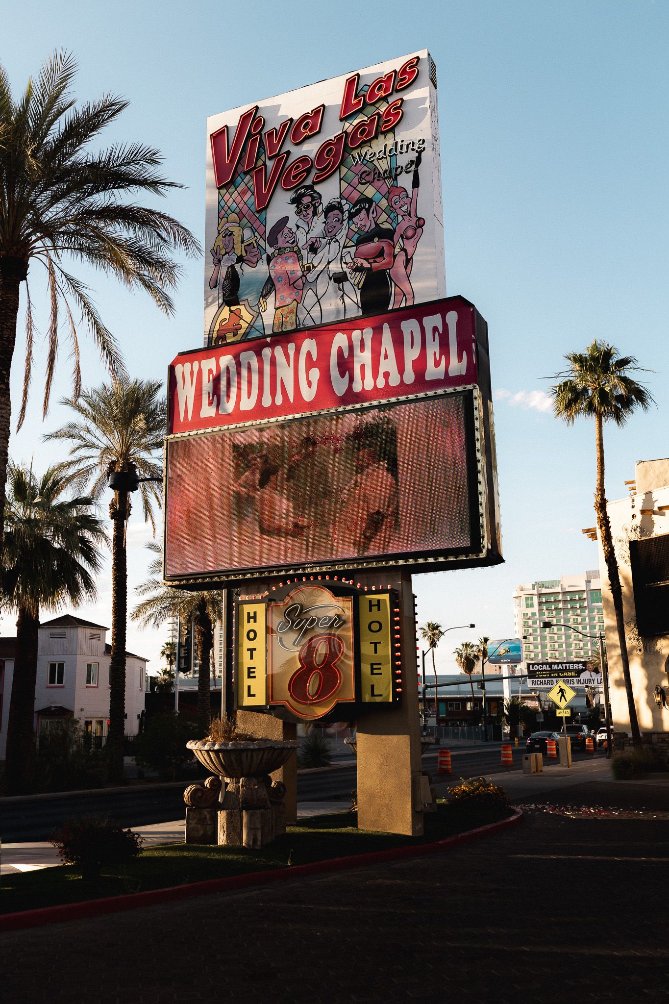 Viva Las Vegas Wedding Chapel sign with palm trees and Hotel 8 marquee on the Las Vegas Strip.