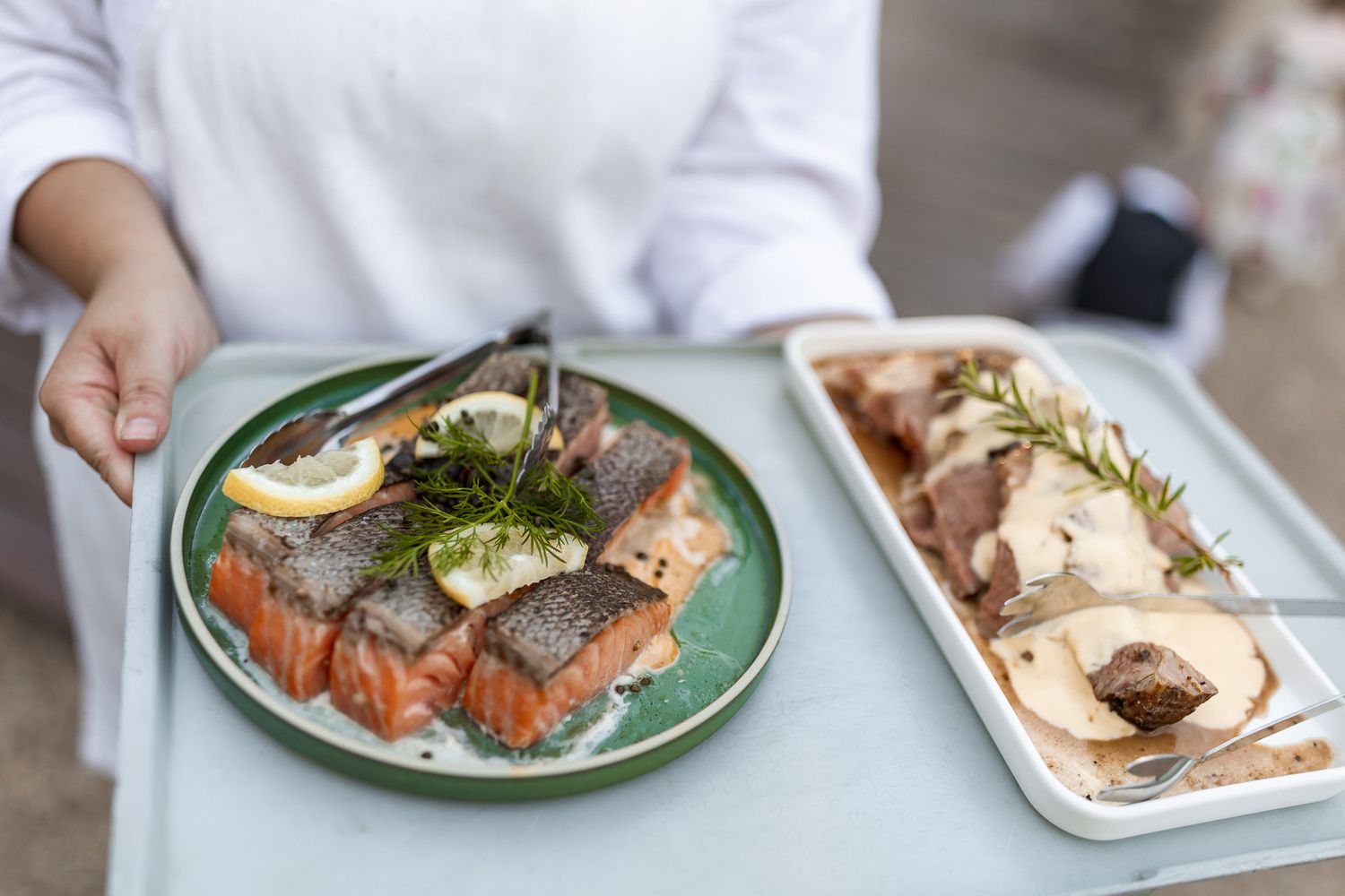 Chef serving fresh salmon and seafood dishes on elegant plates at a restaurant.