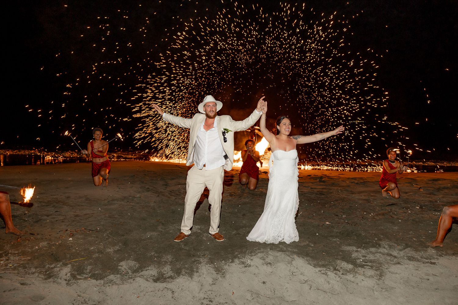 Bride and groom celebrate with sparks flying around them during spectacular beach wedding reception.