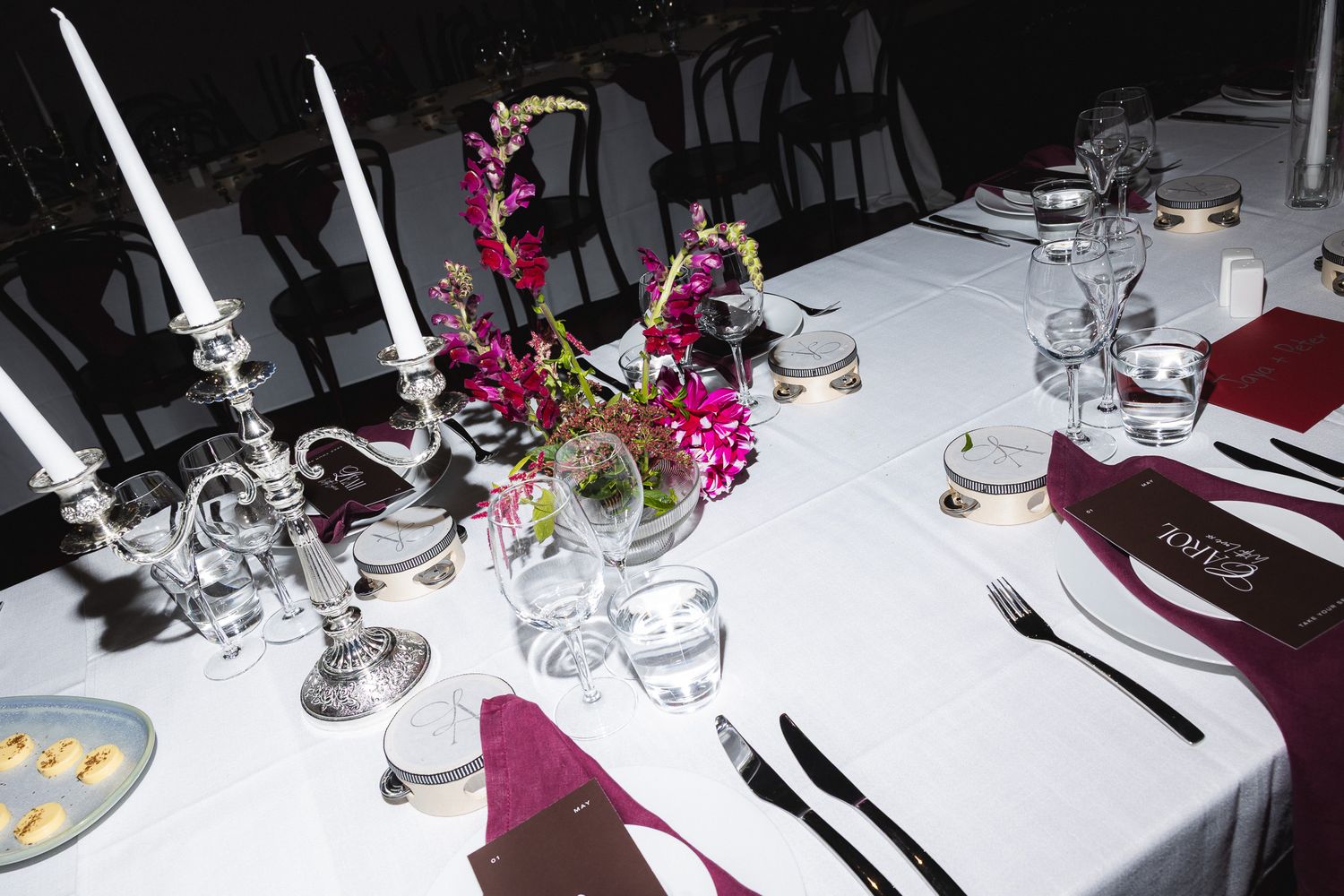 Elegant wedding reception table with white linens, silver candelabra, pink floral centerpiece, and formal place settings.