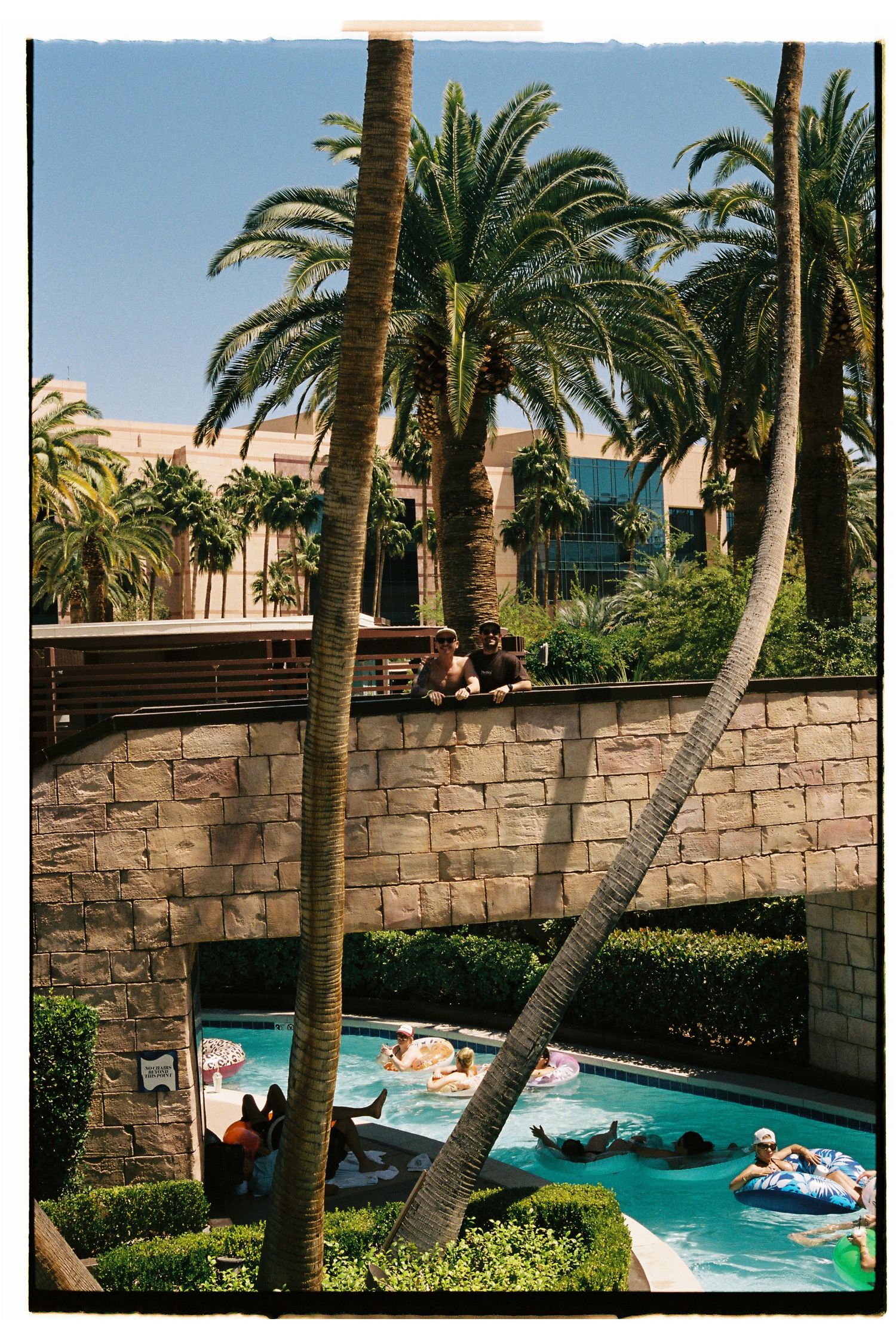 Guests float in a lazy river pool surrounded by palm trees at a Las Vegas resort.