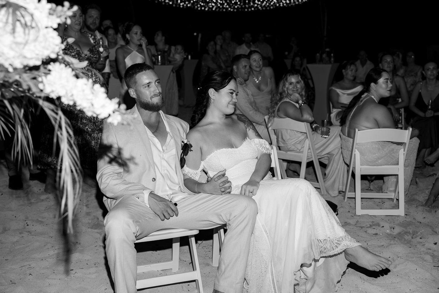 Black and white photo of bride and groom seated together during outdoor evening wedding reception.