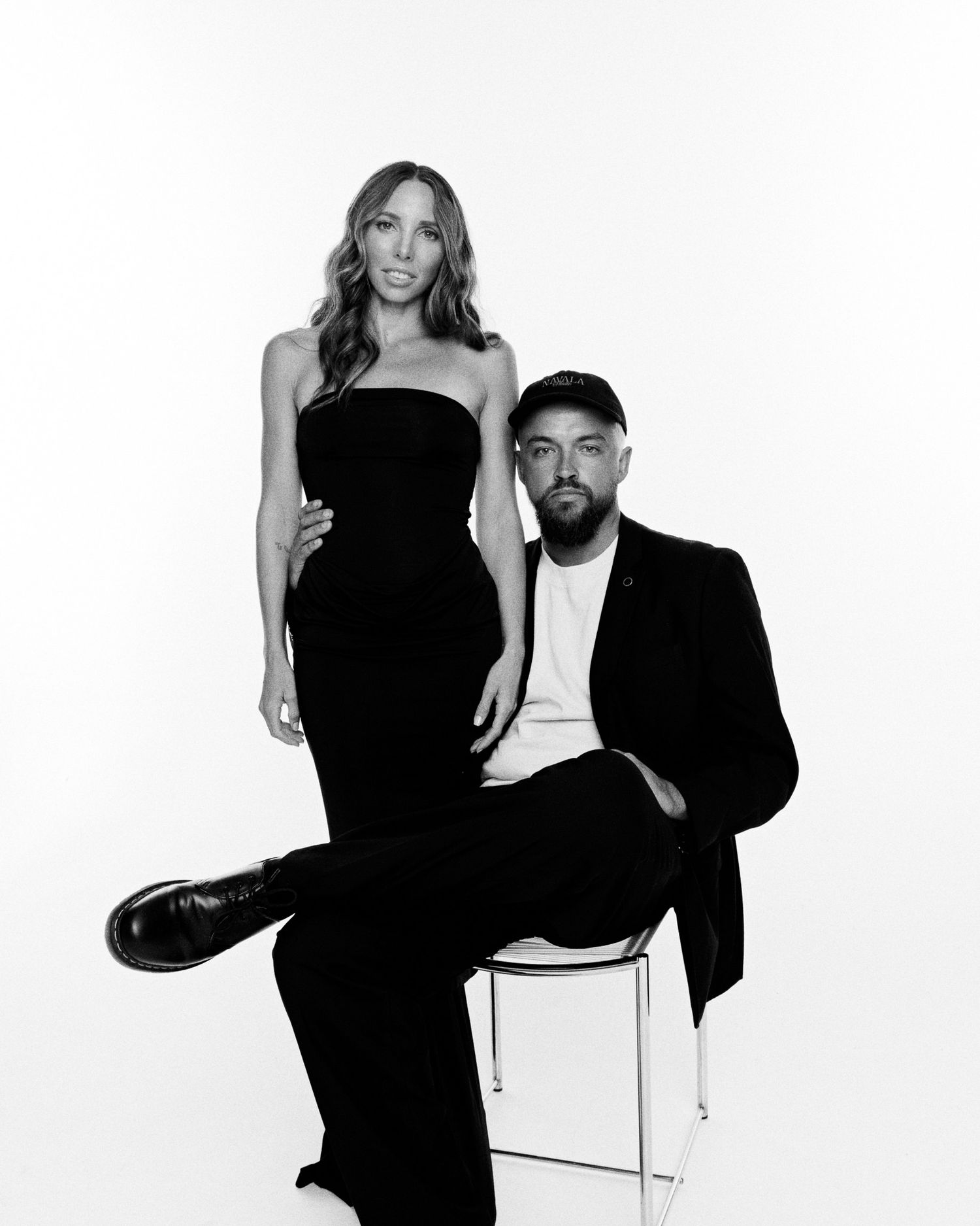Stylish couple poses in black and white portrait, woman in strapless gown and man in black suit.