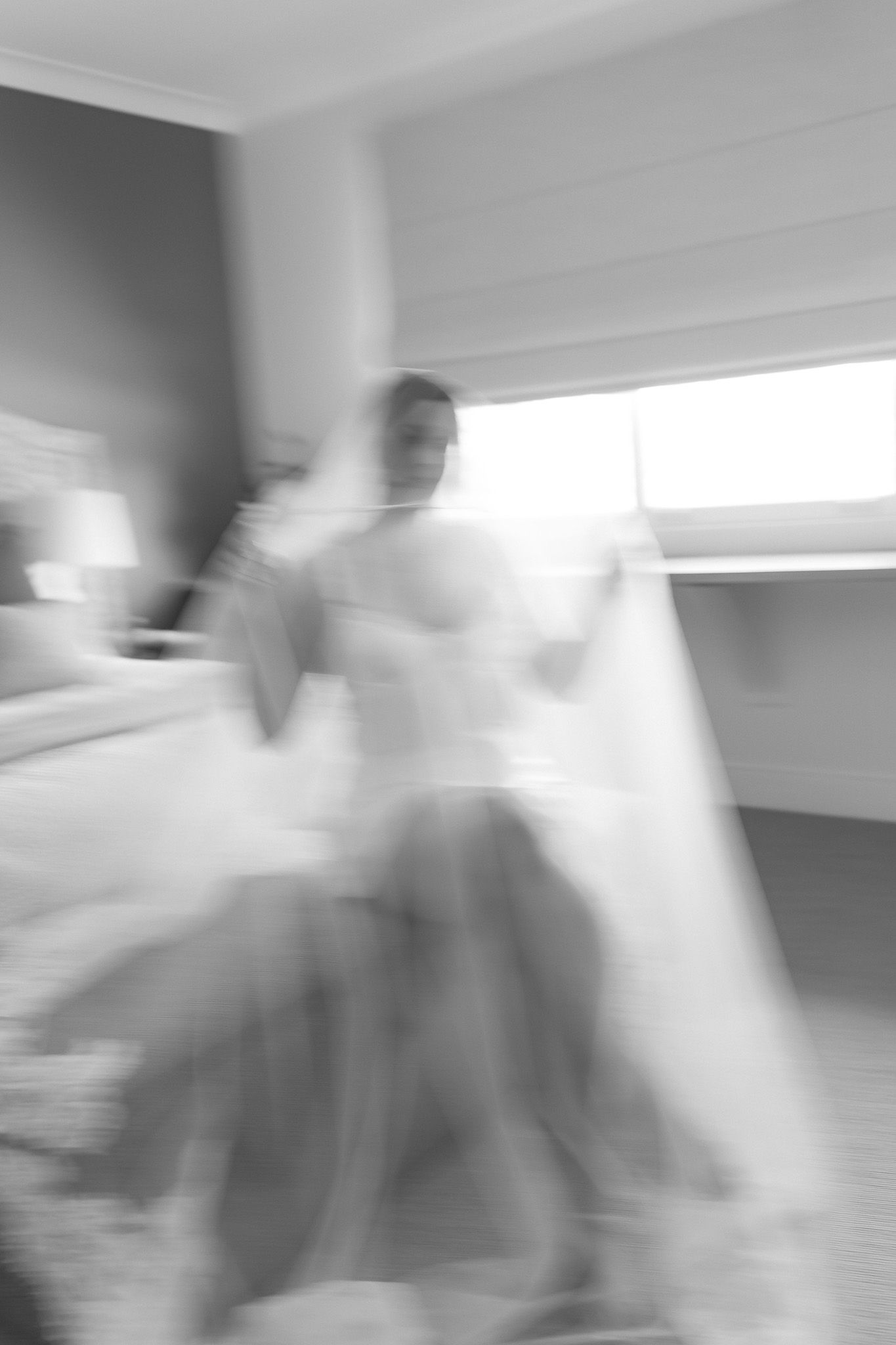 Blurred black and white photo of a bride in a wedding dress, captured with motion blur in an elegant room.