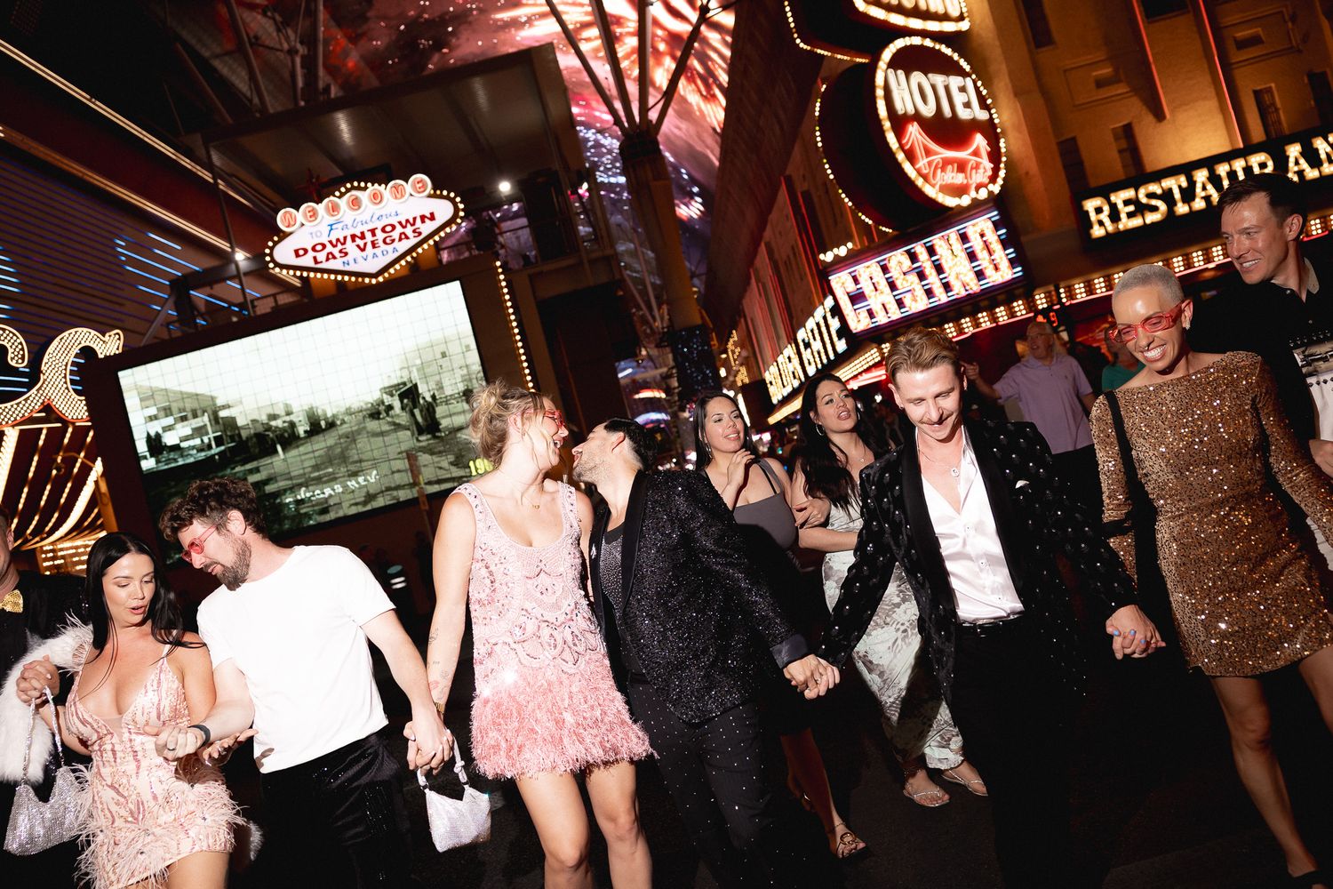 Wedding party celebrating and walking through the Fremont Street Experience in Las Vegas at night.