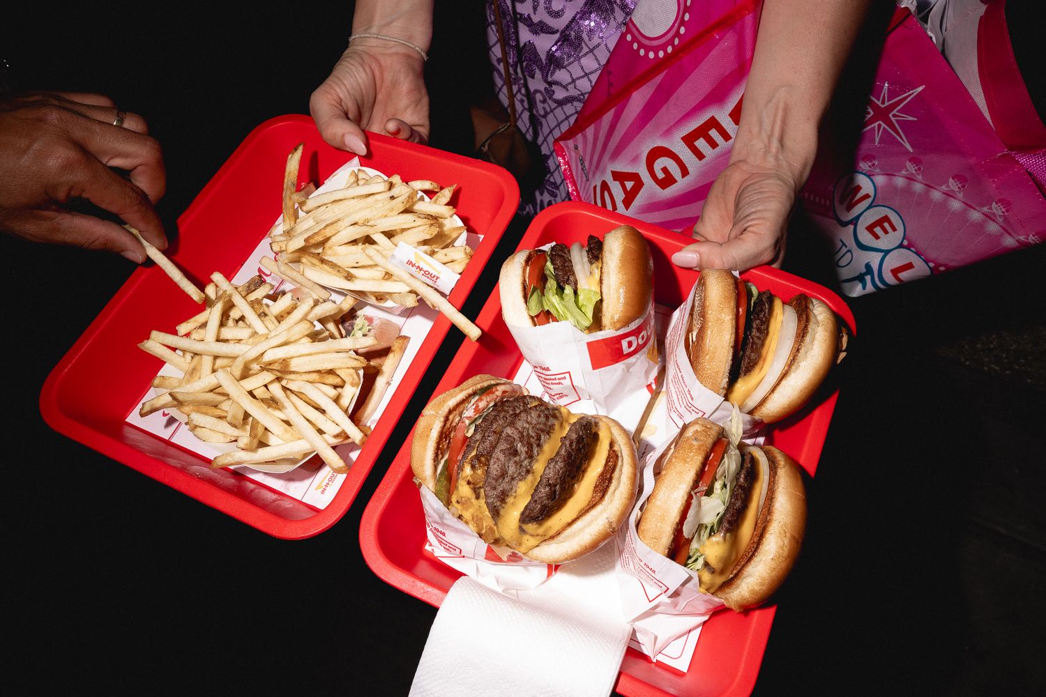In-N-Out Burger burgers and fries served on red trays as late-night wedding reception snacks.