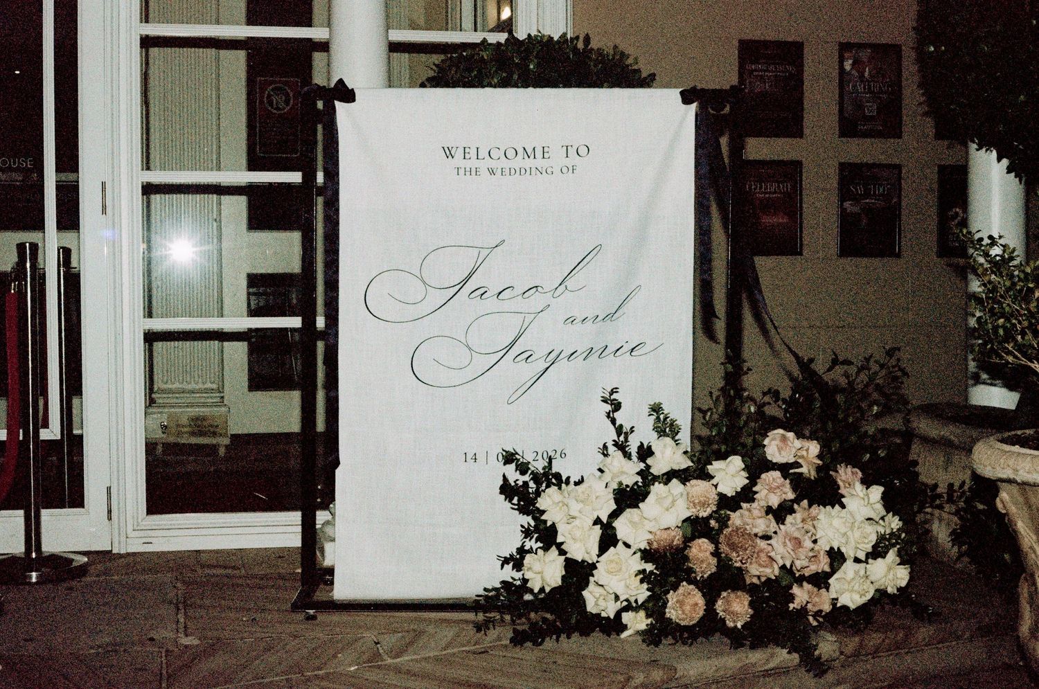 Wedding welcome sign for Jacob and Jaynice surrounded by white and pink floral arrangements.