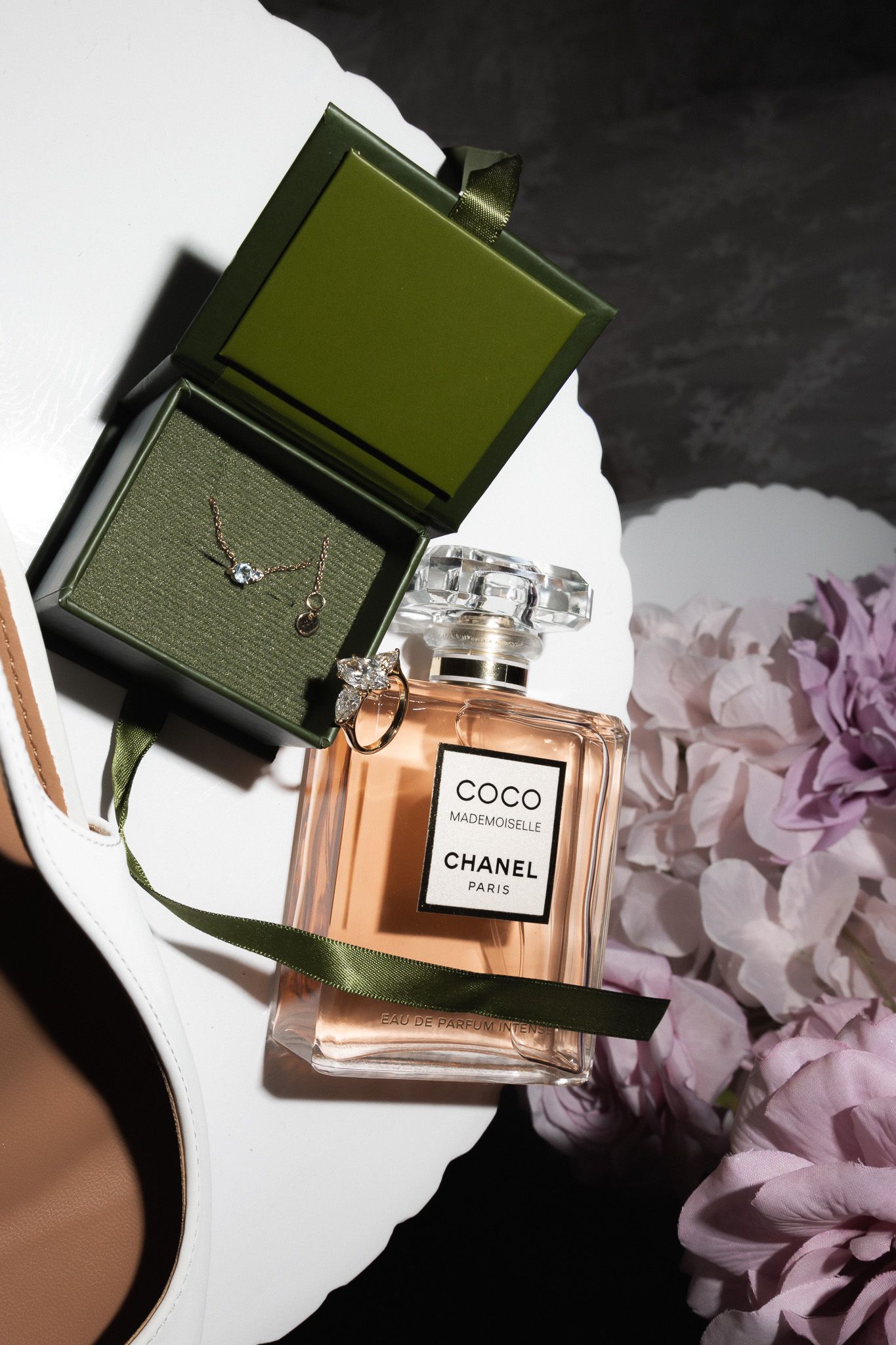 Coco Mademoiselle Chanel Paris perfume bottle beside a green jewelry box with flowers.