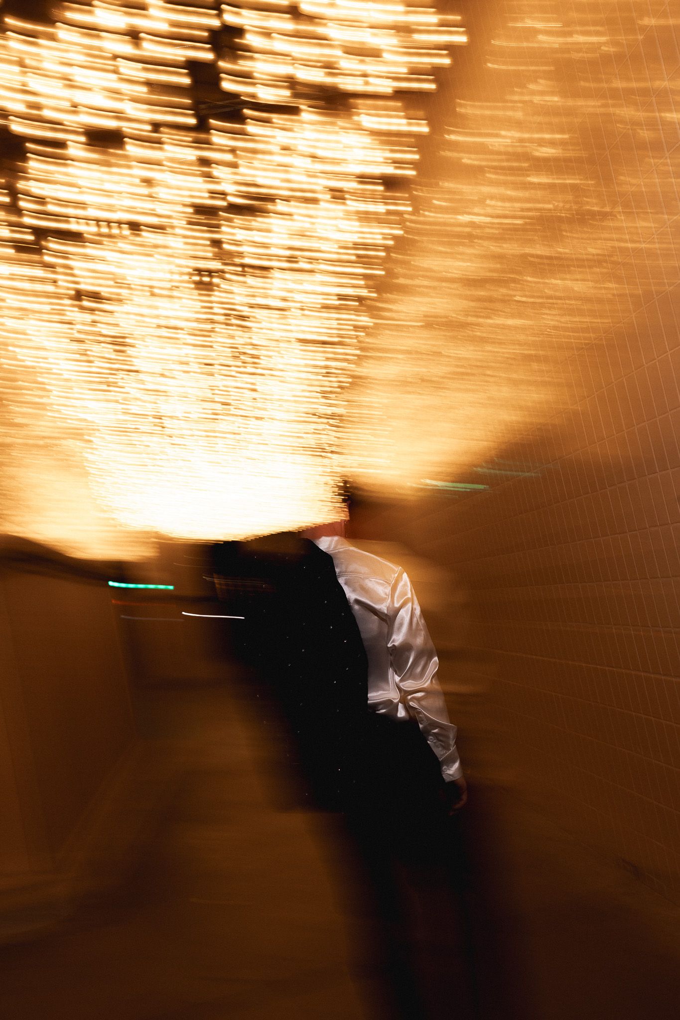 Motion blur captures a person in a white shirt walking past glowing golden lights at night in Las Vegas.