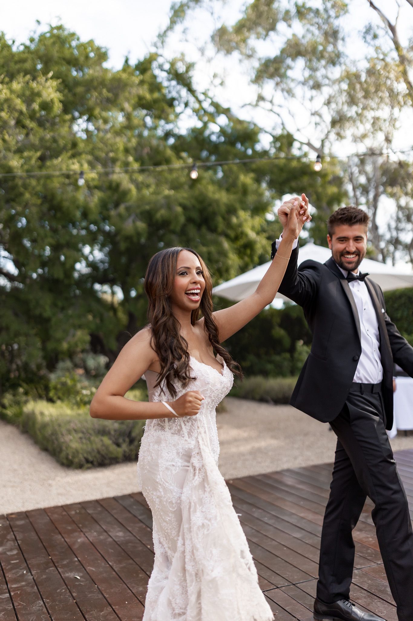 Joyful bride and groom sharing first dance at outdoor wedding.