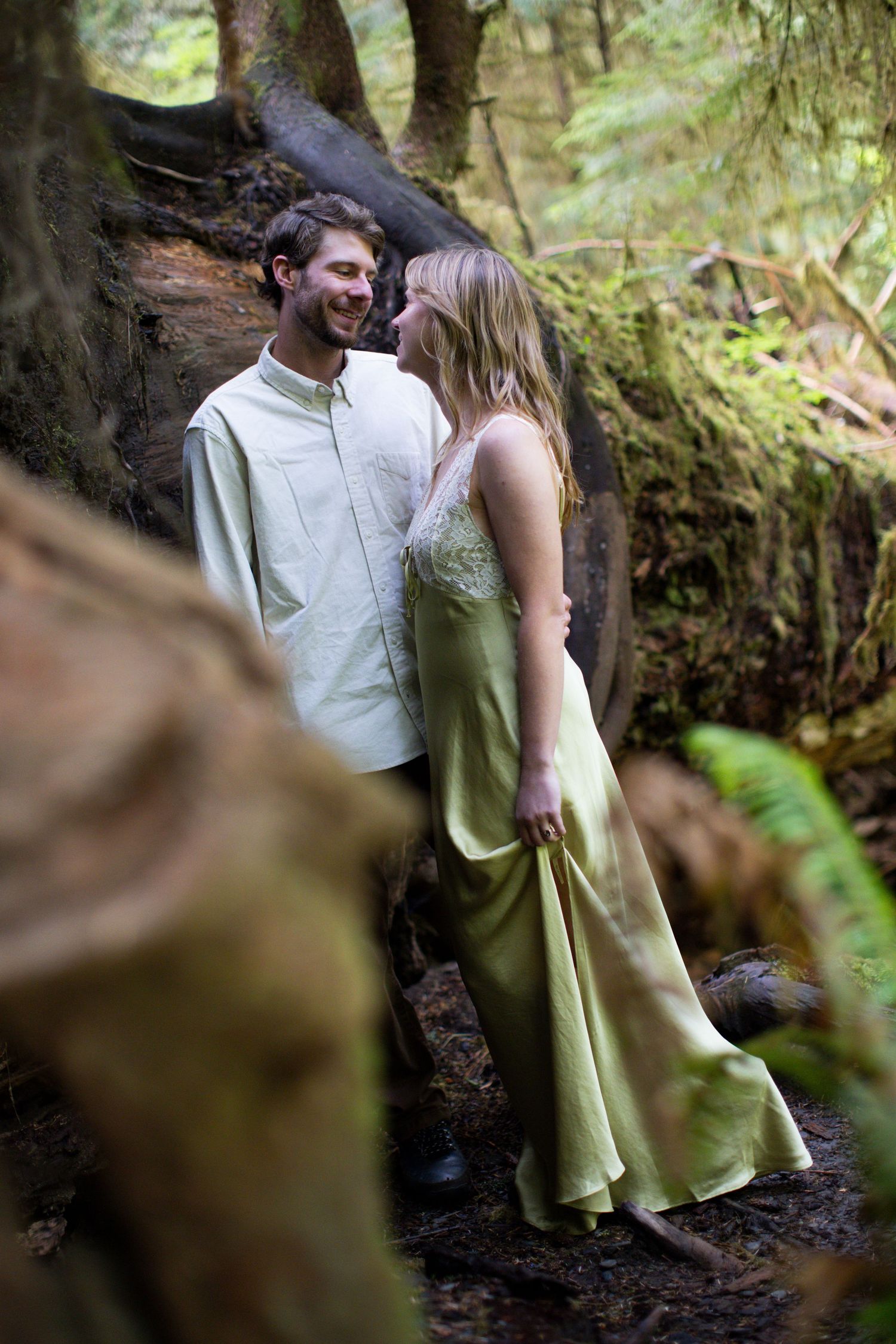 Couple sharing a tender moment together in a lush green mossy forest setting.
