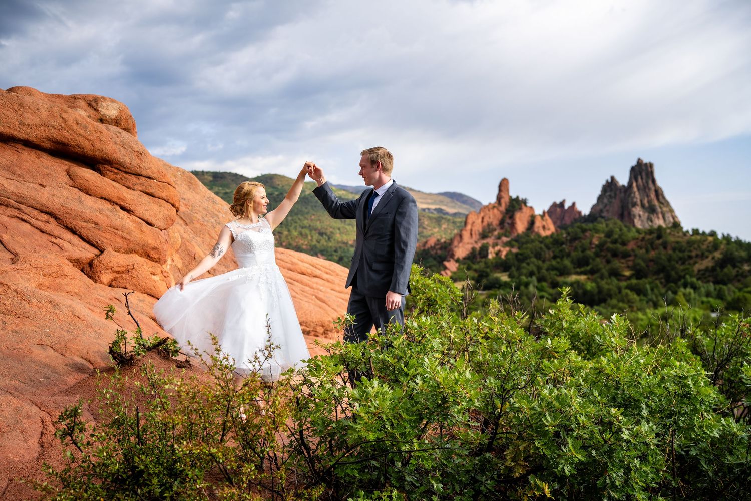 A bride and groom dance among red rock formations at Garden of the Gods in Colorado.