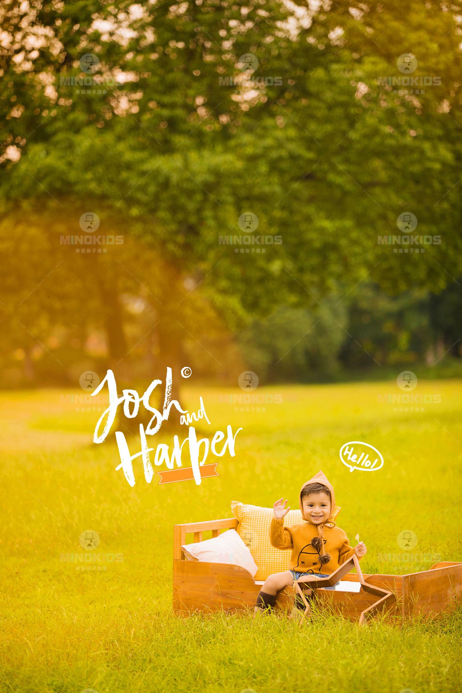 Cheerful toddler in mustard hoodie sits on wooden prop bed in golden sunlit green park setting.