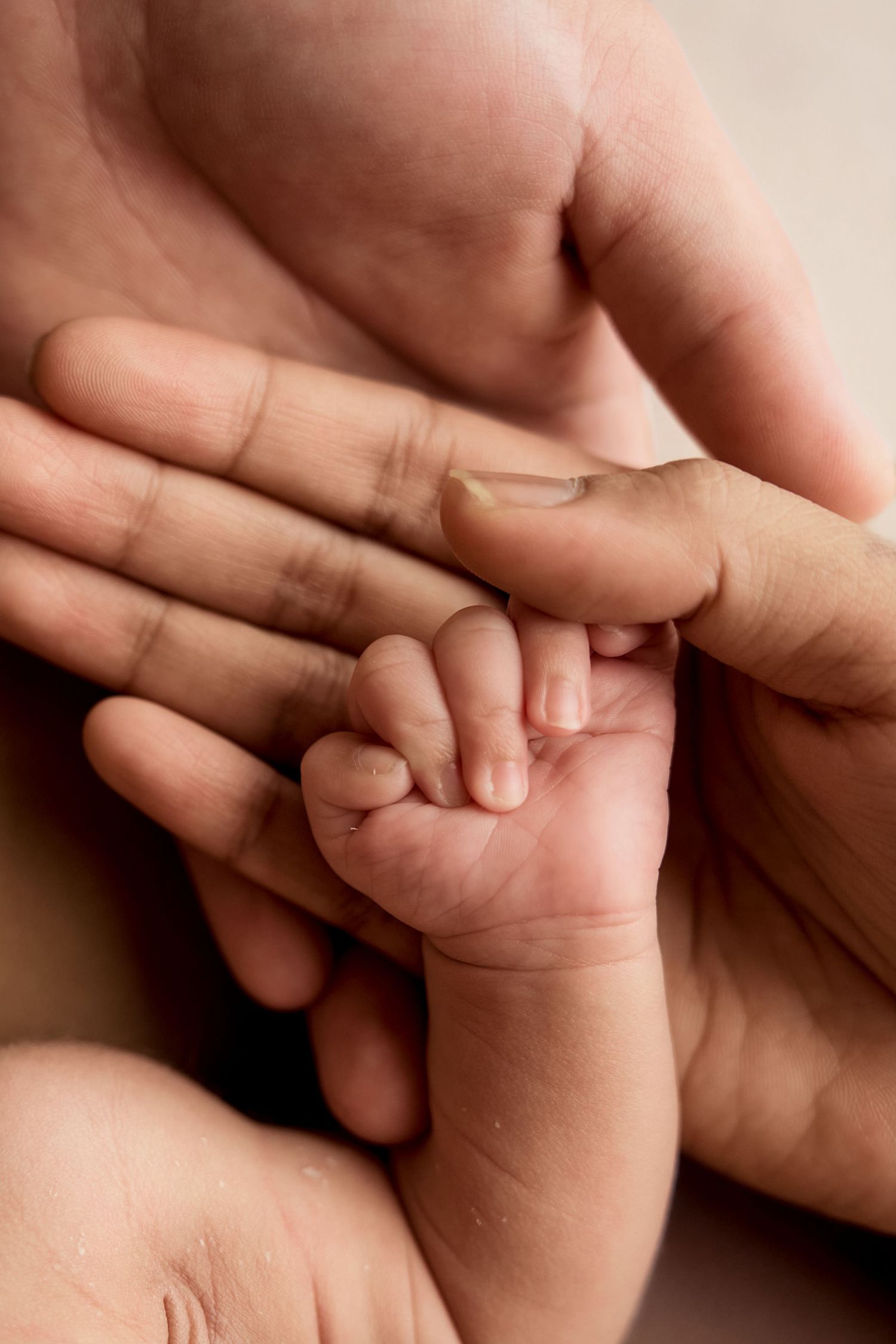 A newborn baby's tiny hand gently gripping an adult's finger, symbolizing love and new life.