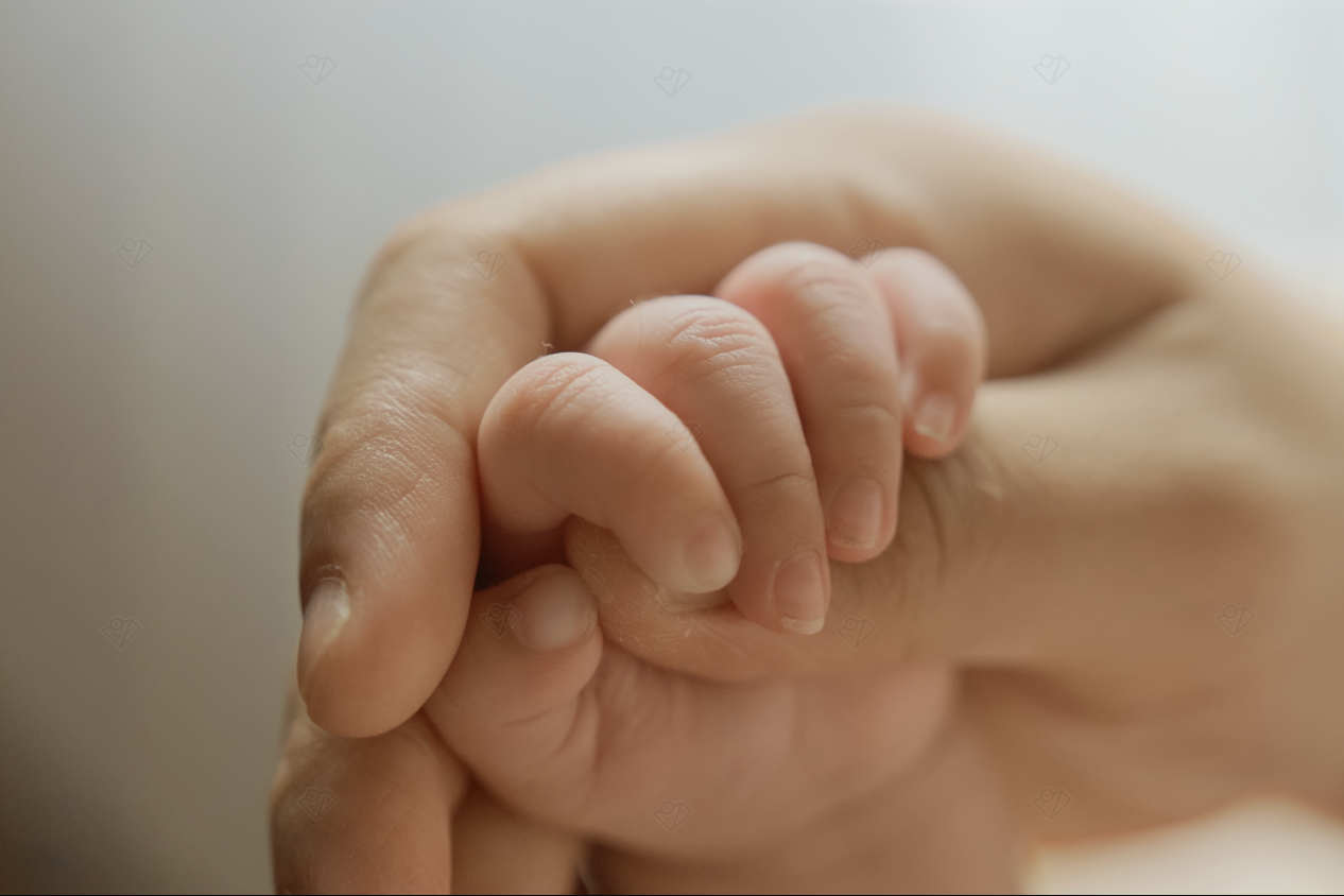 Close-up of a newborn baby's tiny hand grasping an adult's finger, symbolizing love and new life.