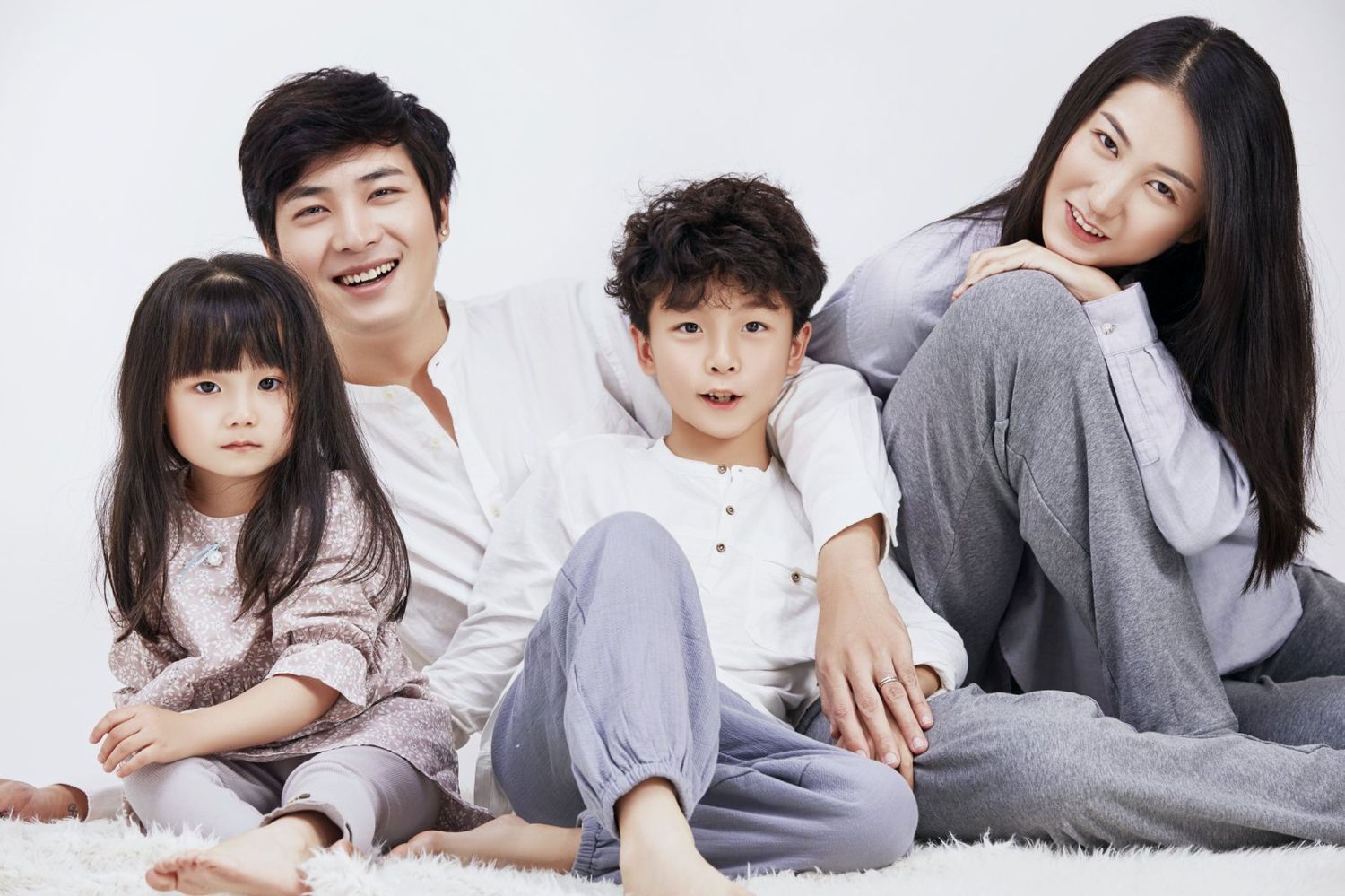 Happy Asian family with two children posing on white background.