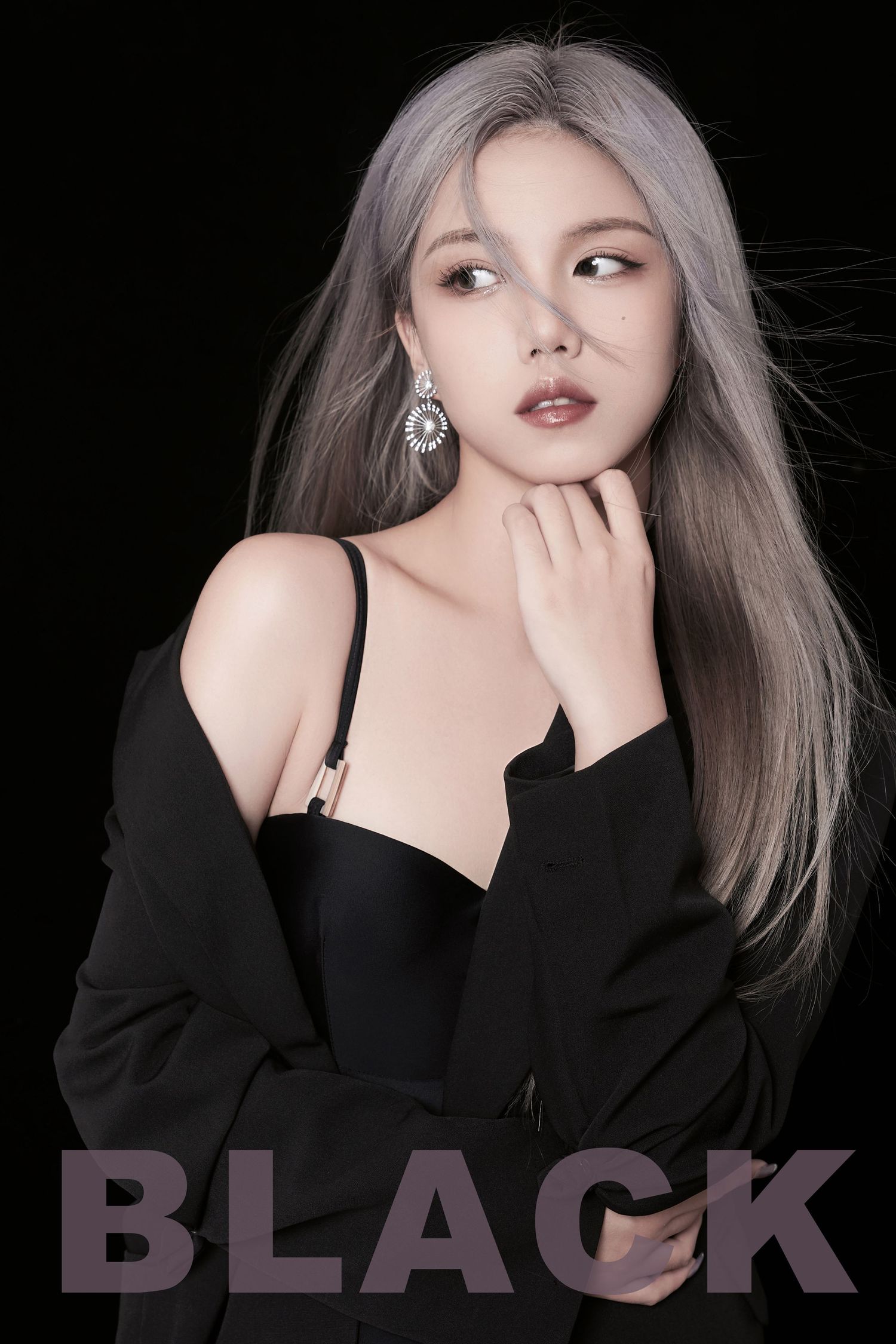 Young woman with silver-gray hair in black outfit and earrings poses against dark background with BLACK text overlay.