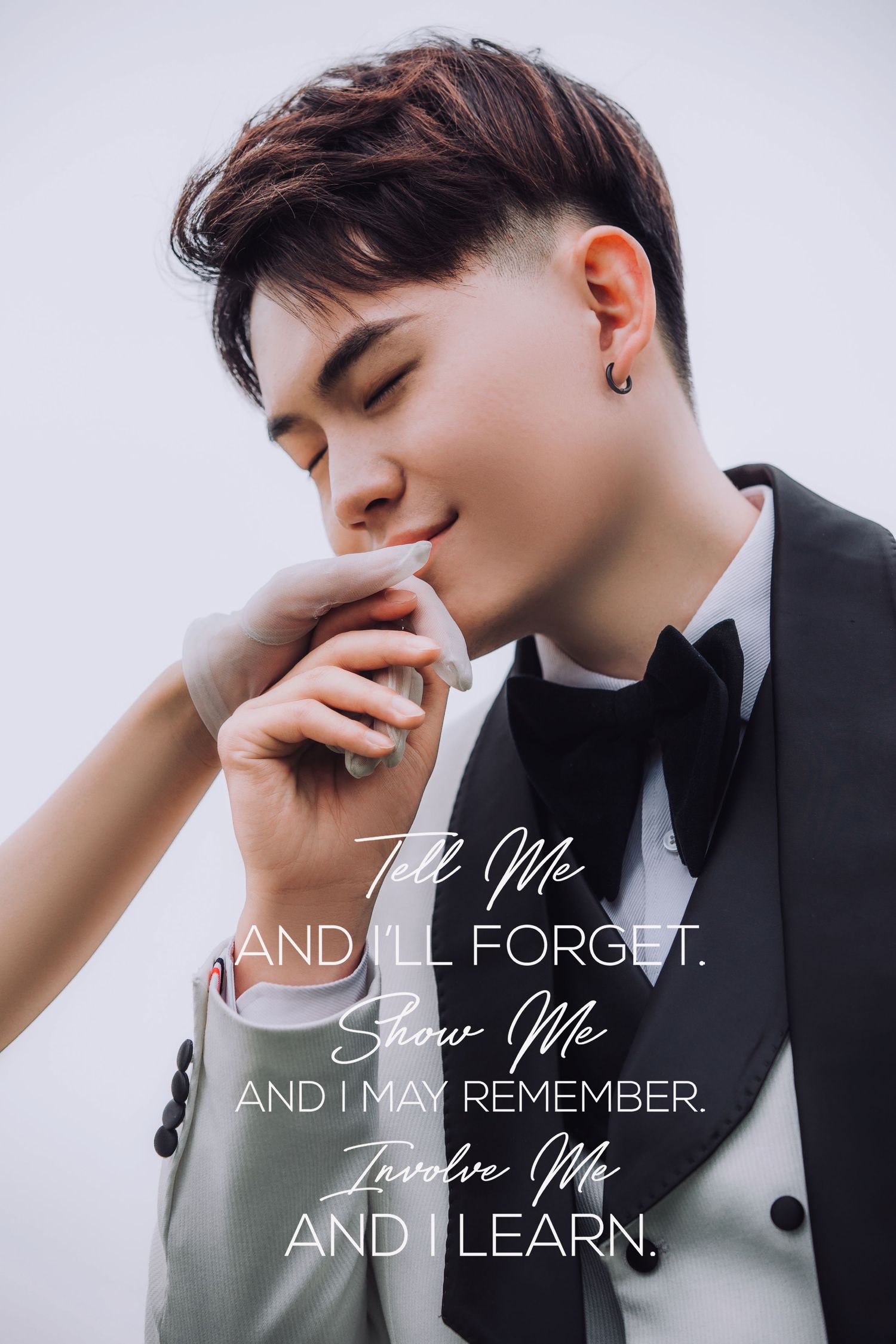 Young Asian groom in tuxedo with bow tie poses thoughtfully with motivational quote overlay.