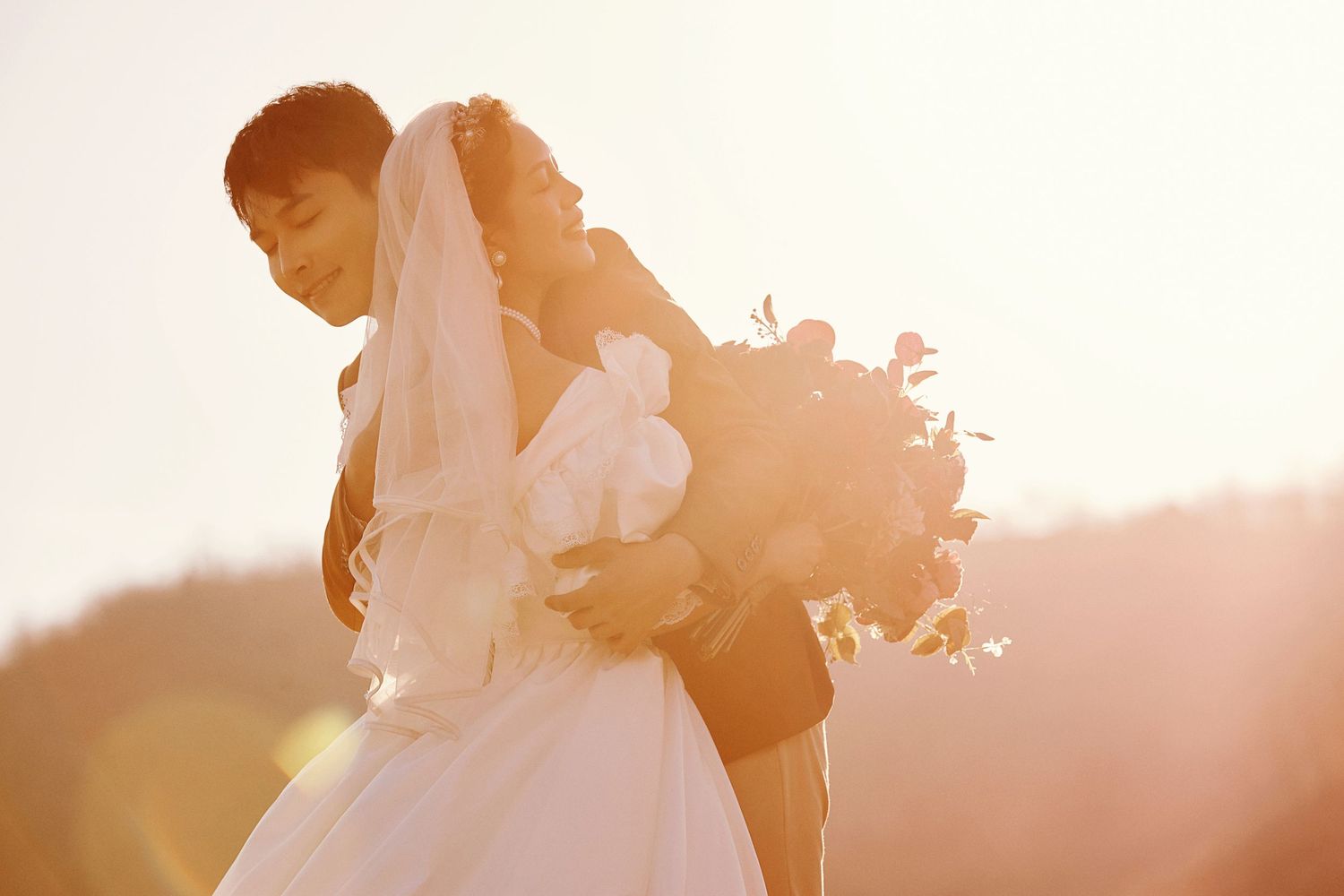 Bride and groom sharing tender moment in warm sunset light.