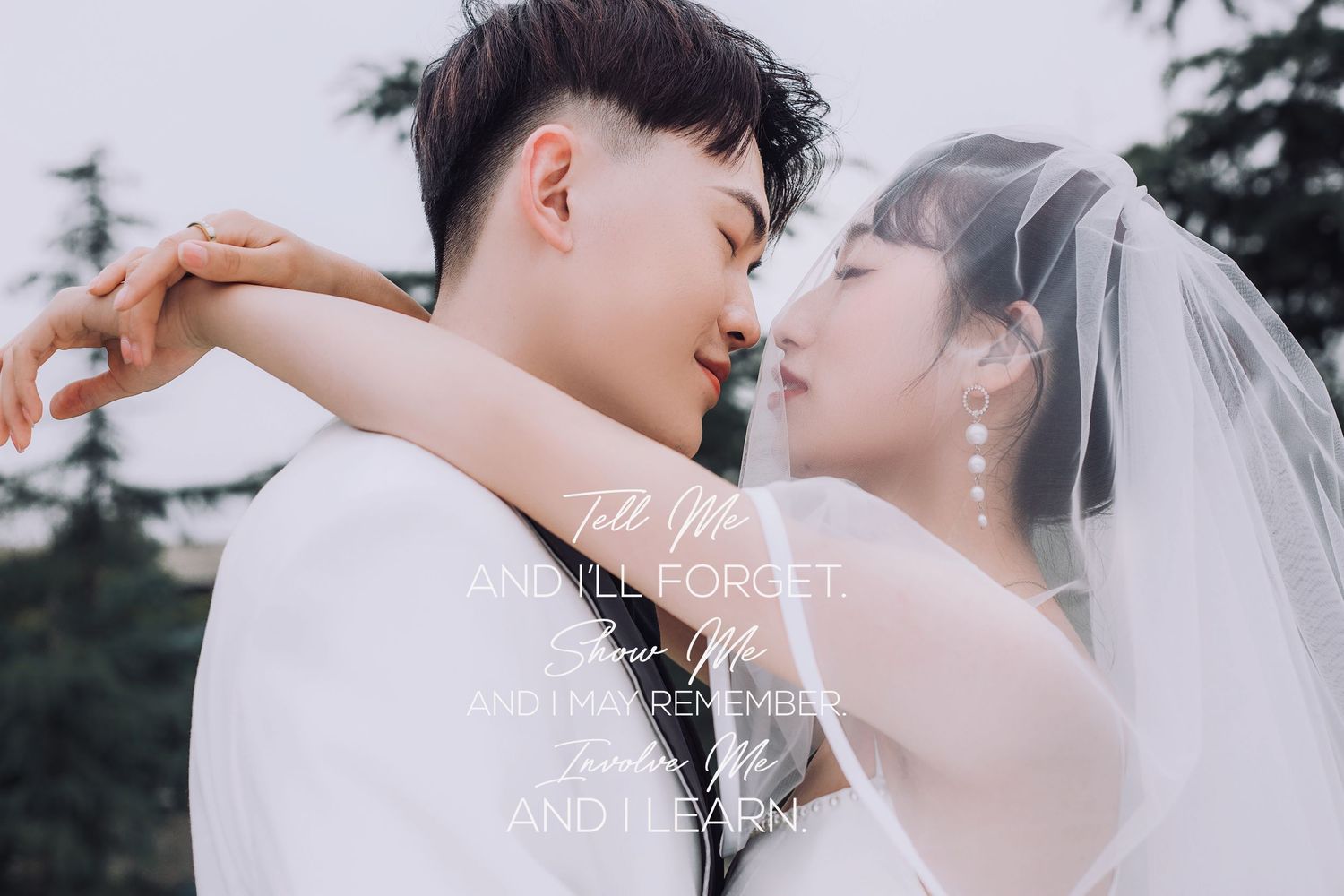 Bride and groom share a tender almost-kiss moment outdoors with soft white veil flowing gently.