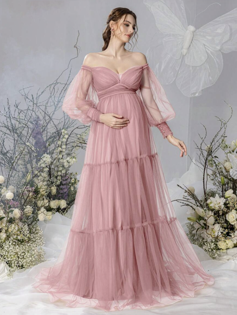 Pregnant woman in dusty pink off-shoulder tulle maternity gown with tiered skirt and sheer long sleeves.