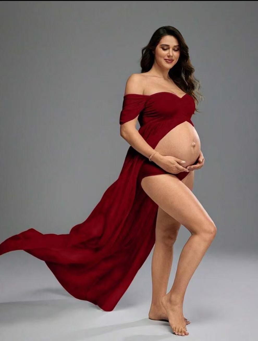 Pregnant woman in red off-shoulder maternity gown with high slit and train.