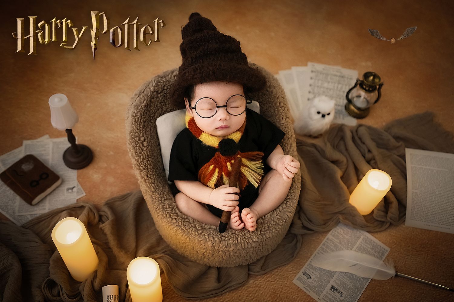 Newborn baby in Harry Potter costume with sorting hat sleeping in cozy bowl with candles and owl.