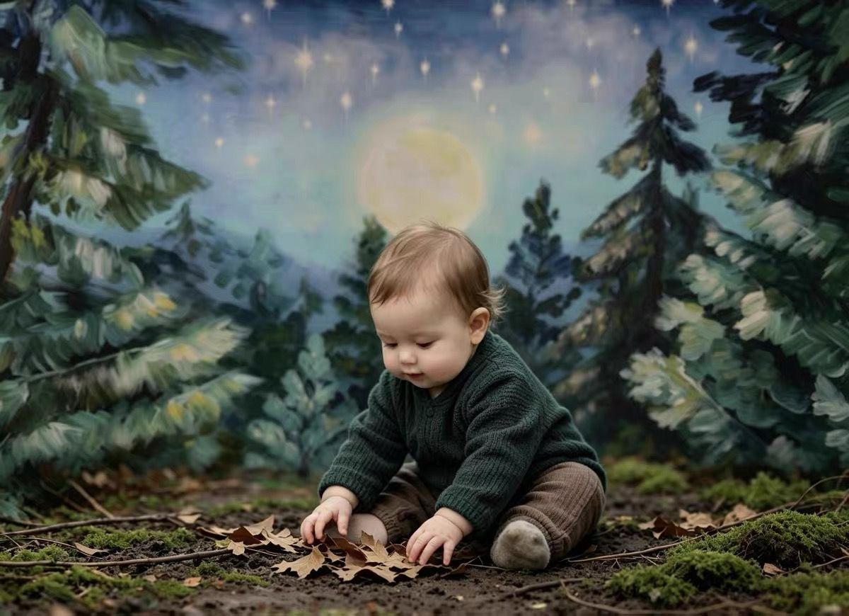 Baby in green outfit plays with autumn leaves on forest floor with pine trees and glowing moon backdrop.