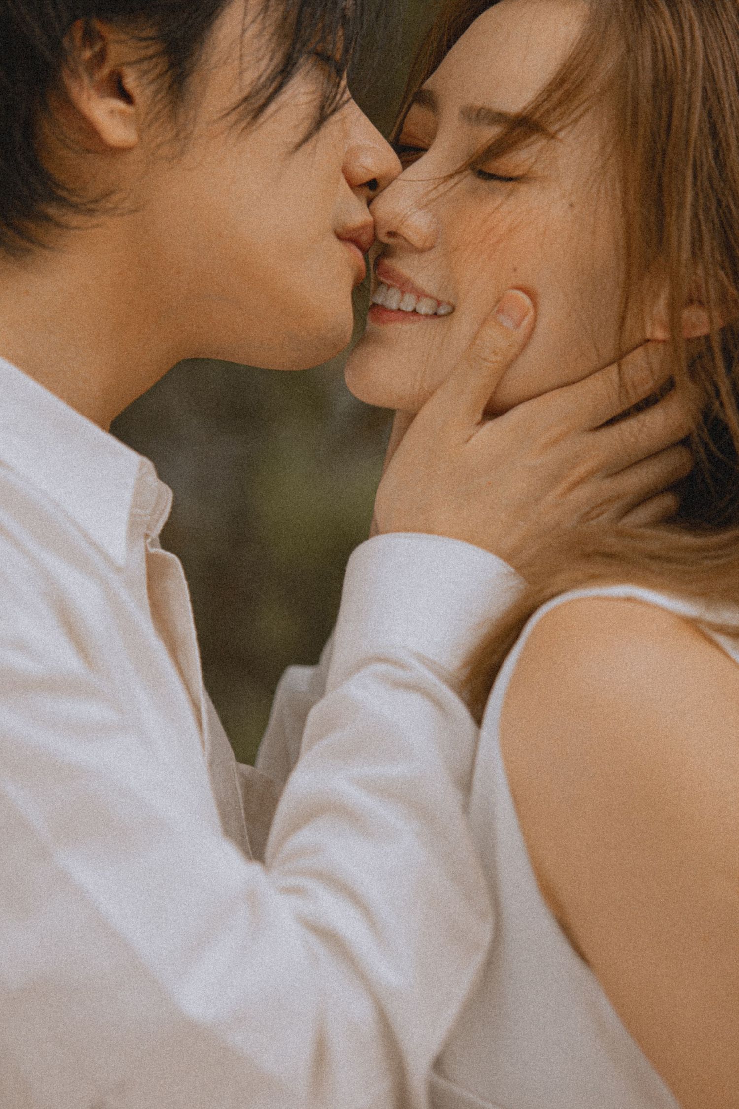 Romantic couple sharing a tender almost-kiss, man gently cupping woman's face with eyes closed.