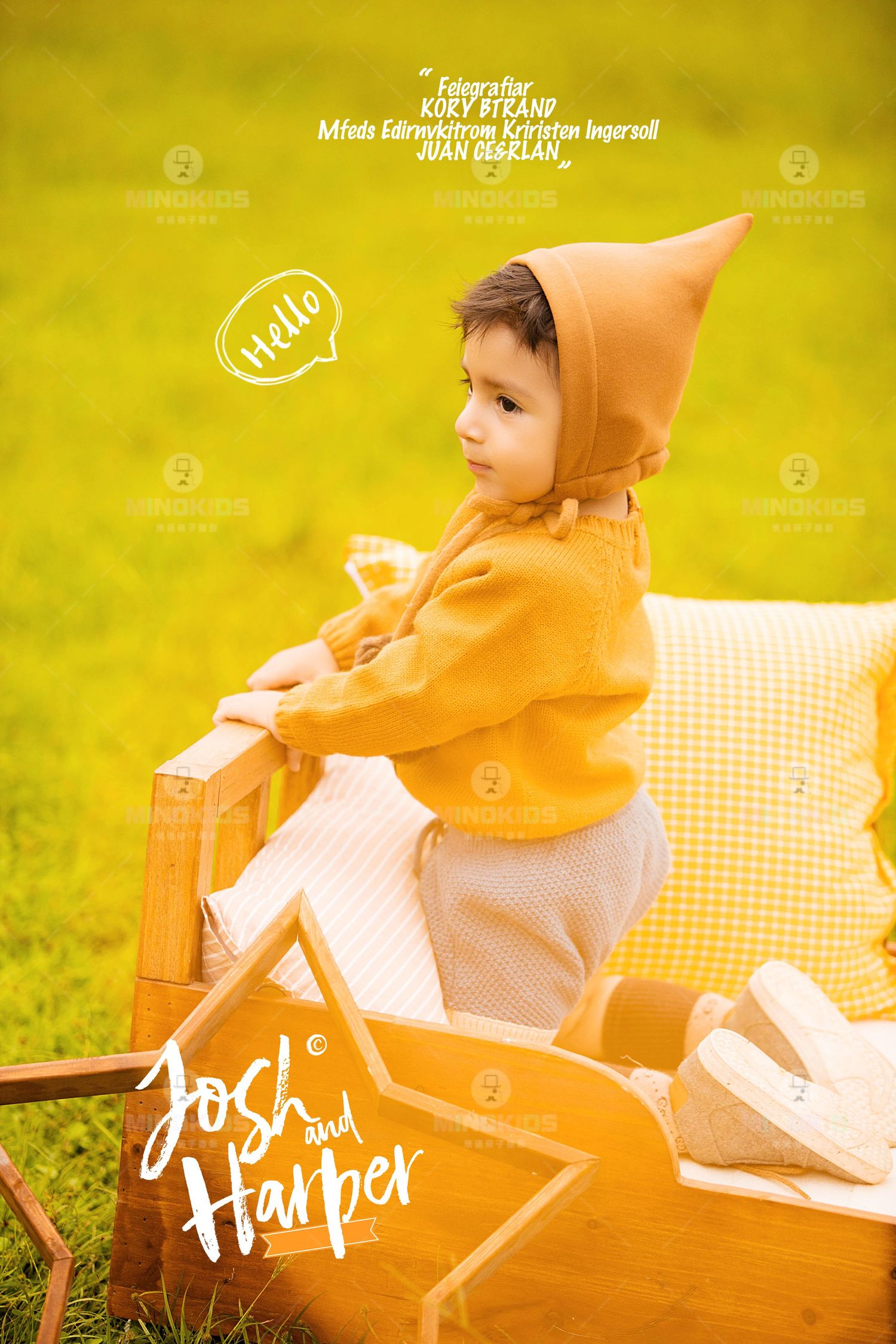 Cute toddler in mustard yellow hooded jacket sits on wooden chair in green field saying Hello.