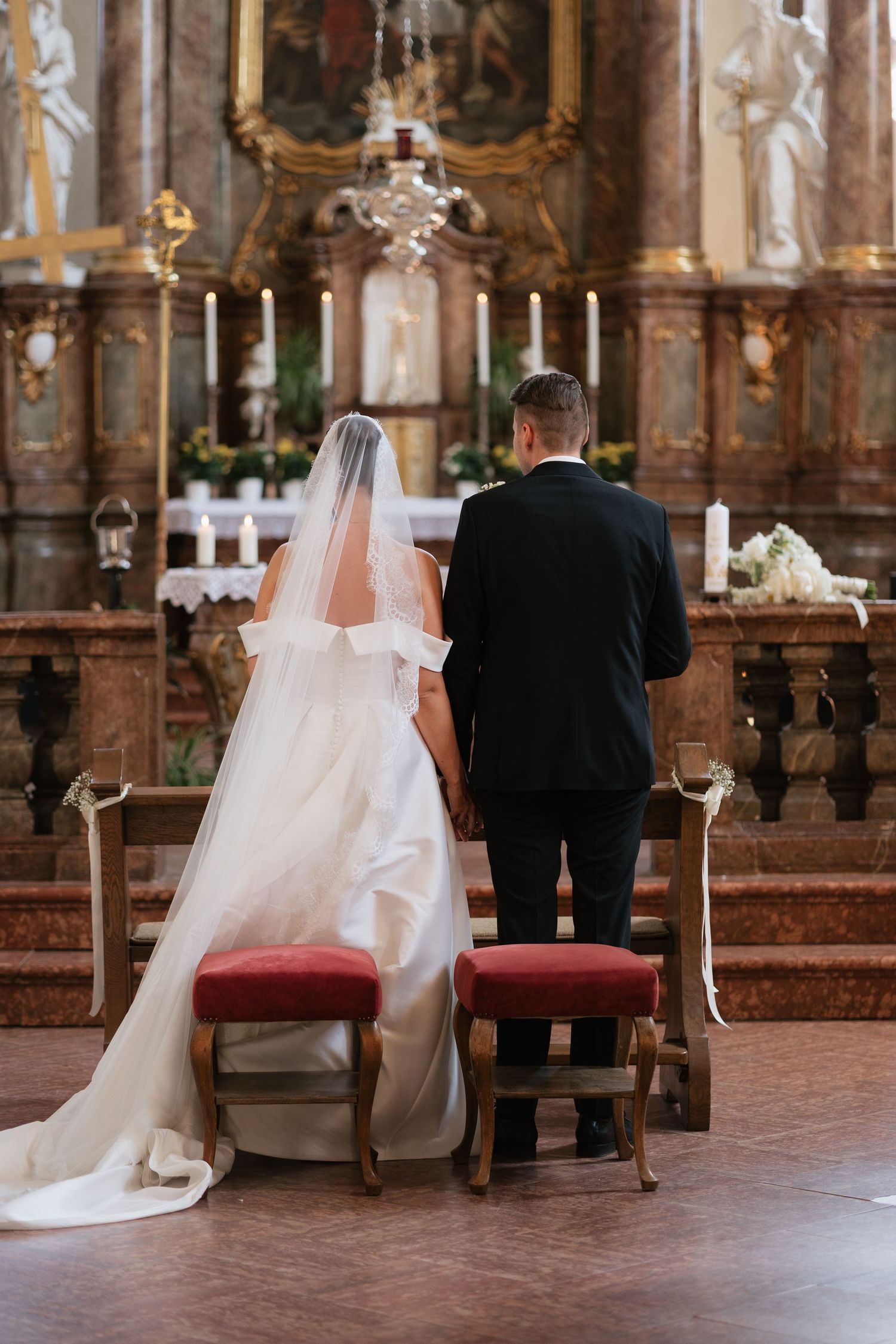 Bride and groom standing at church altar during wedding ceremony, bride wearing white gown with veil.