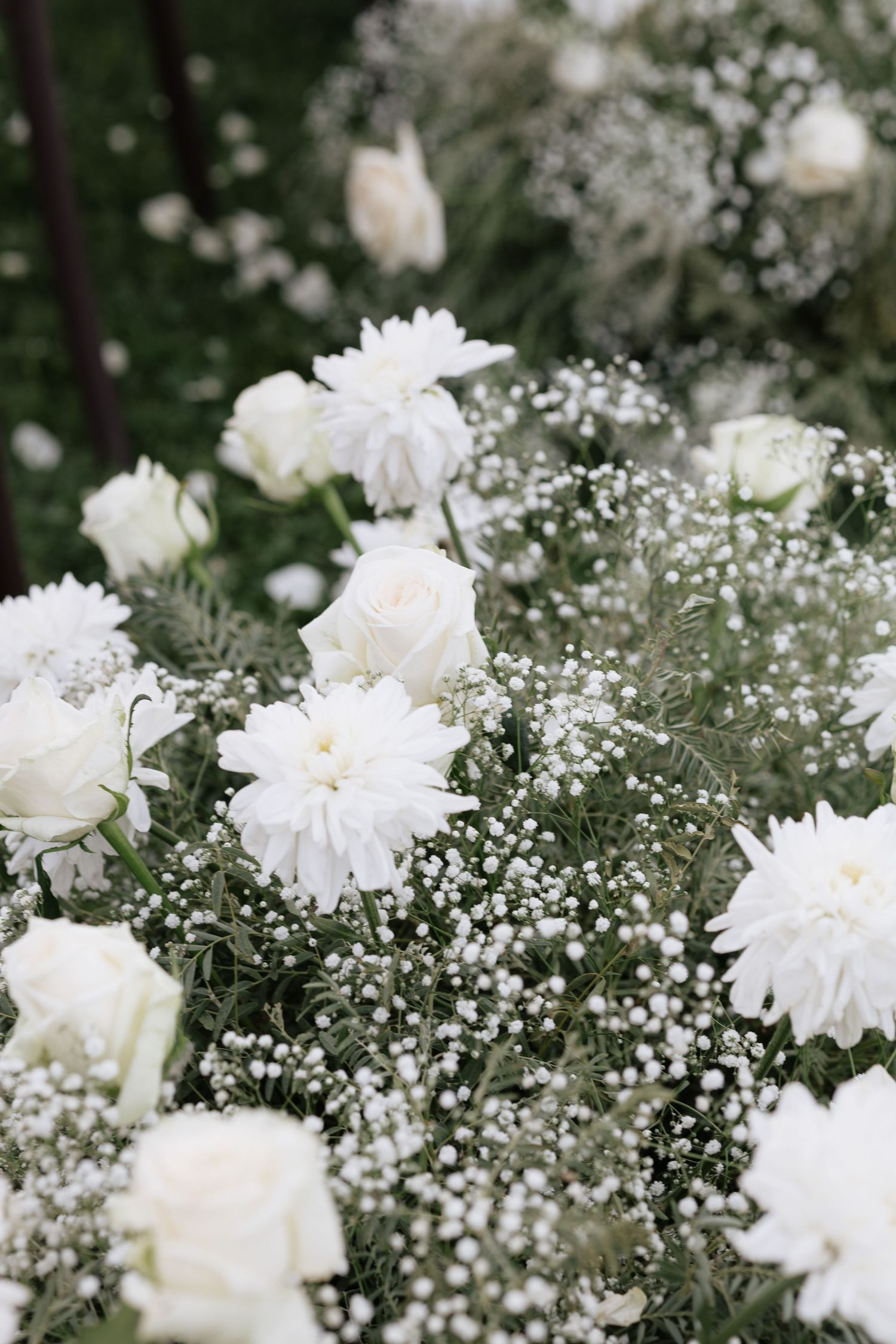 White roses, chrysanthemums, and baby's breath flowers arranged in a lush, elegant floral display.