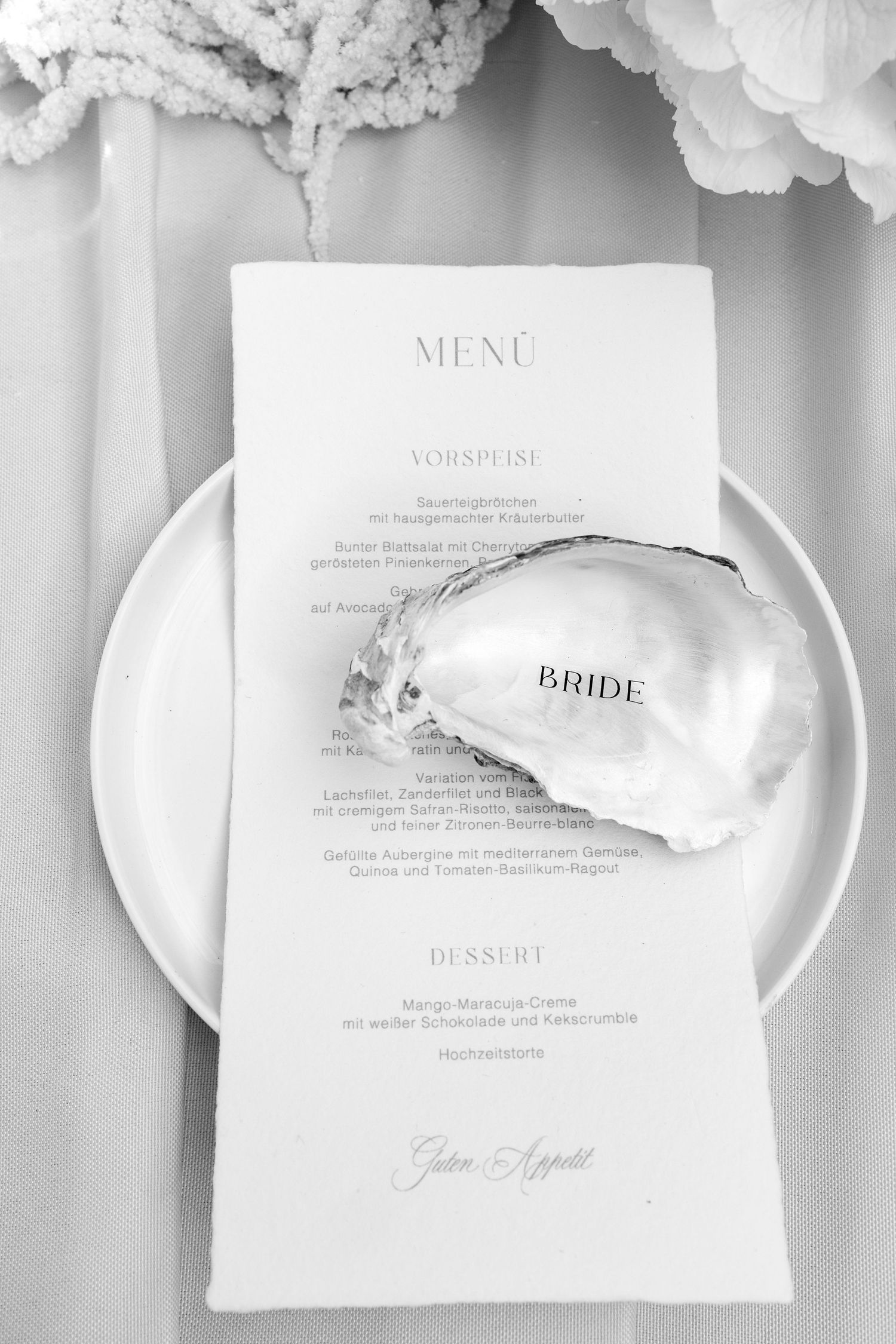 Elegant black and white wedding menu card with a seashell bride place card on a white plate.