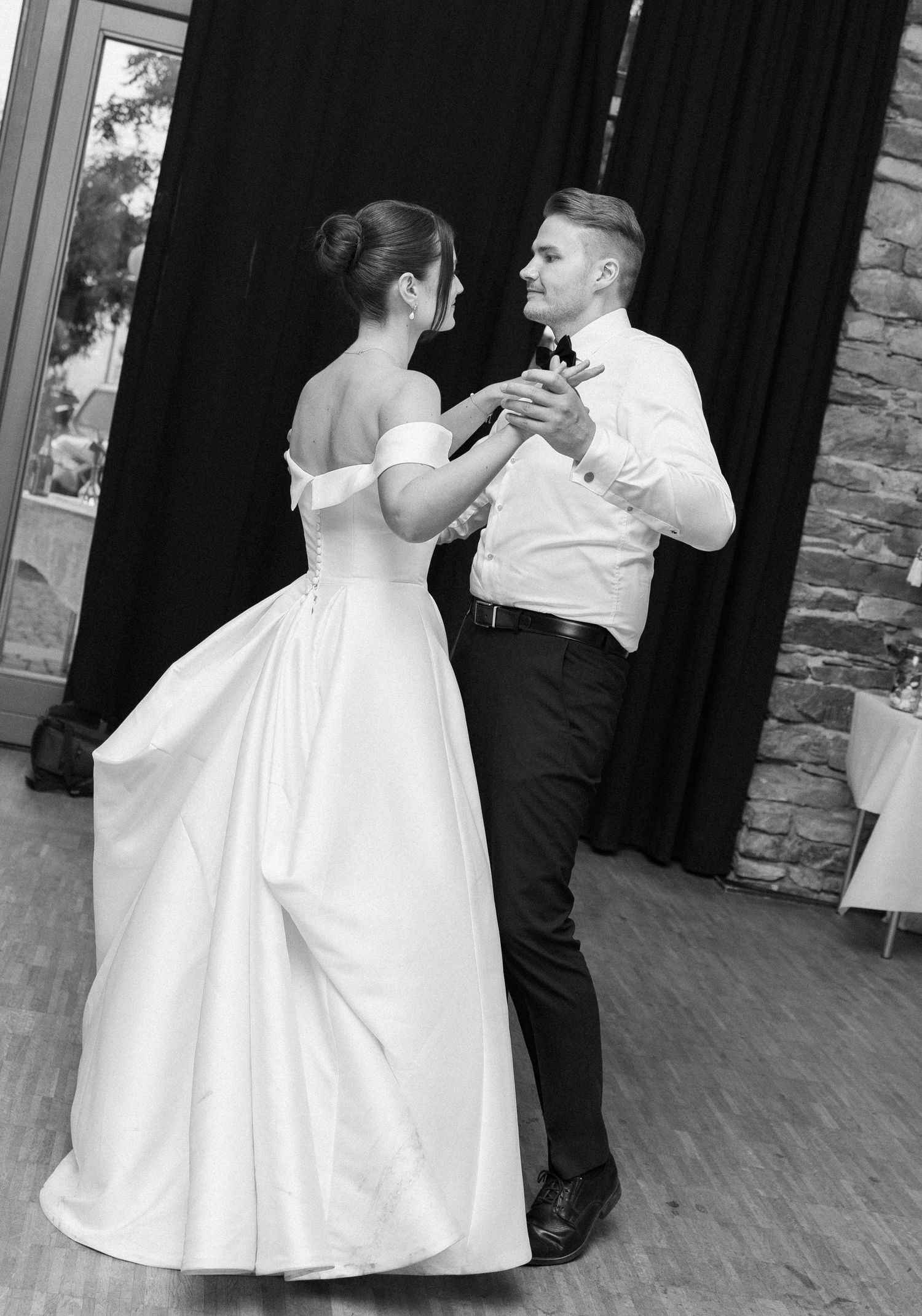Black and white photo of a bride and groom sharing their first dance at a wedding reception.