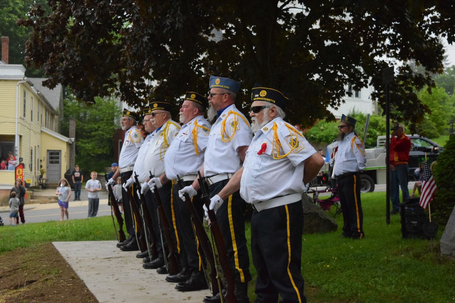 Veterans and color guard members stand at attention during a memorial service ceremony.