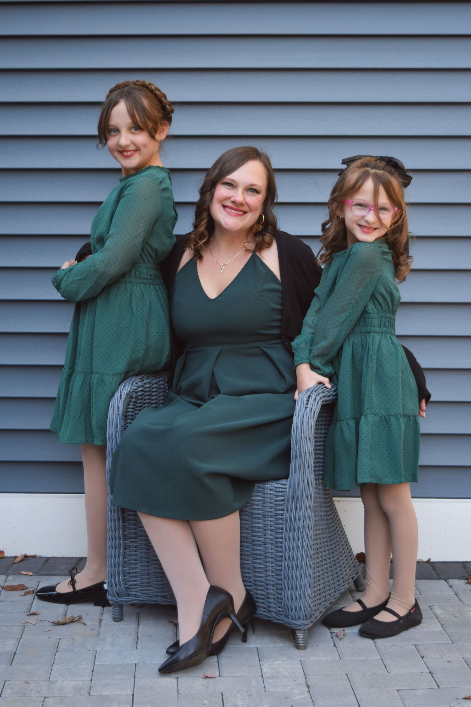 A series of playful poses in front of blue siding showing two people in coordinating green and black outfits.
