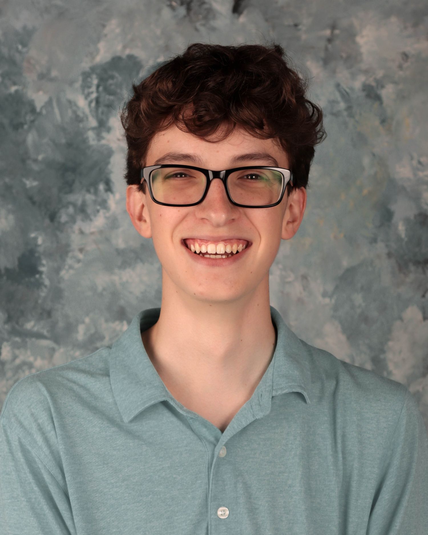 Student headshot showing someone in glasses and a light blue polo shirt against a gray mottled backdrop.