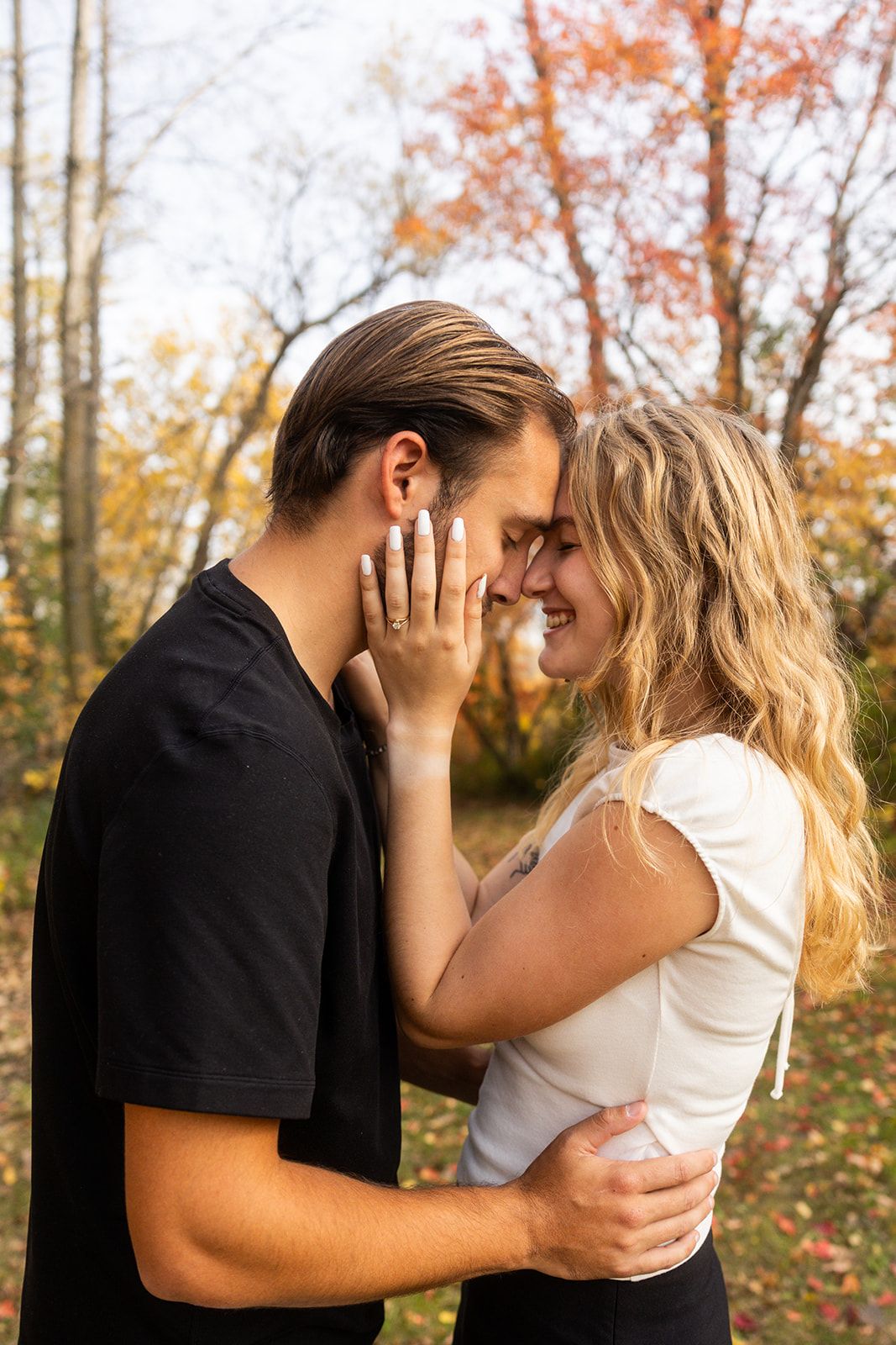 An intimate moment between two people captured in a fall forest setting.